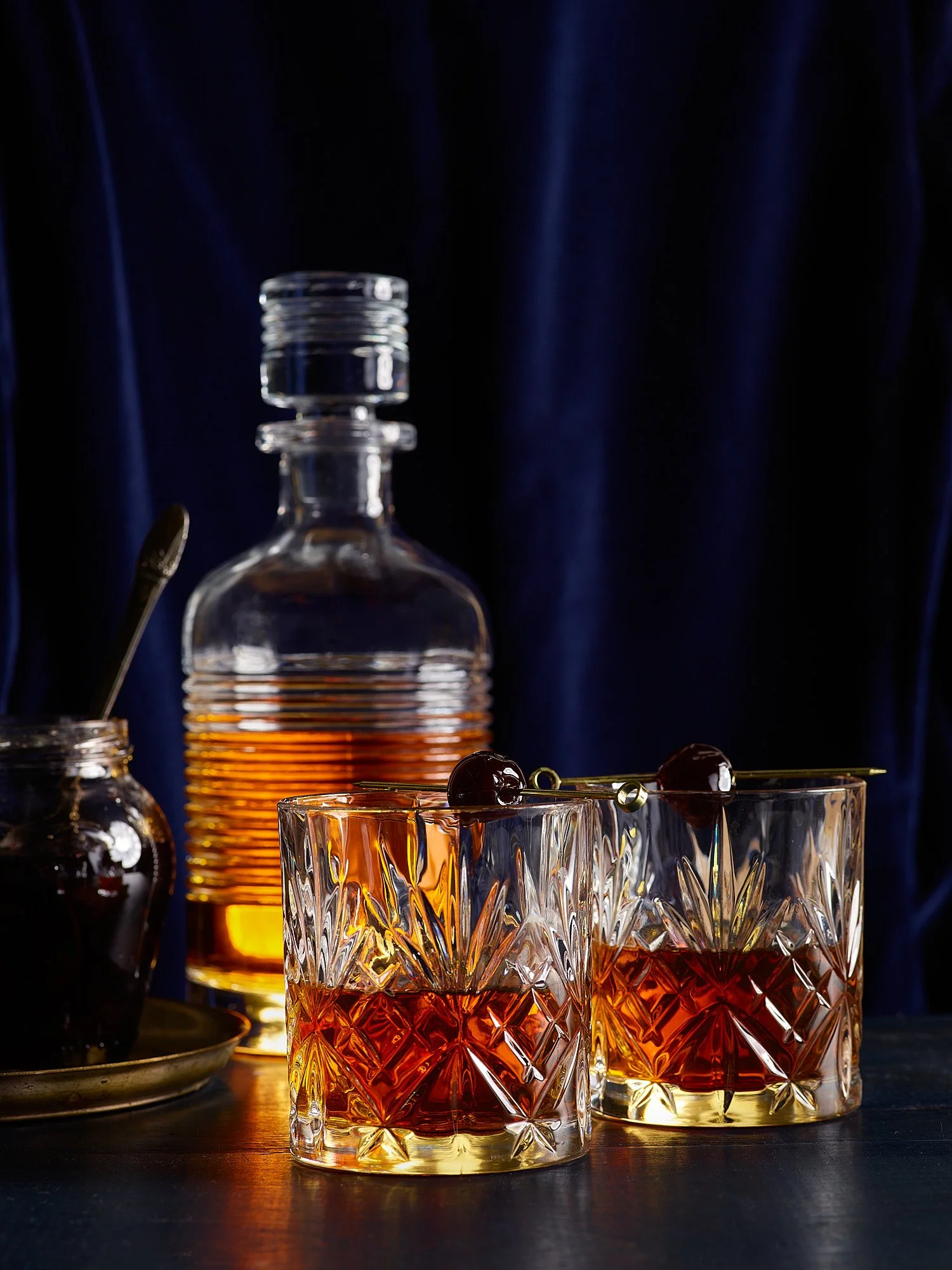 Whiskey decanter crystal glasses dark blue velvet spirits advertising photography by Dhanraj Emanuel, beverage photographer Greensboro NC
