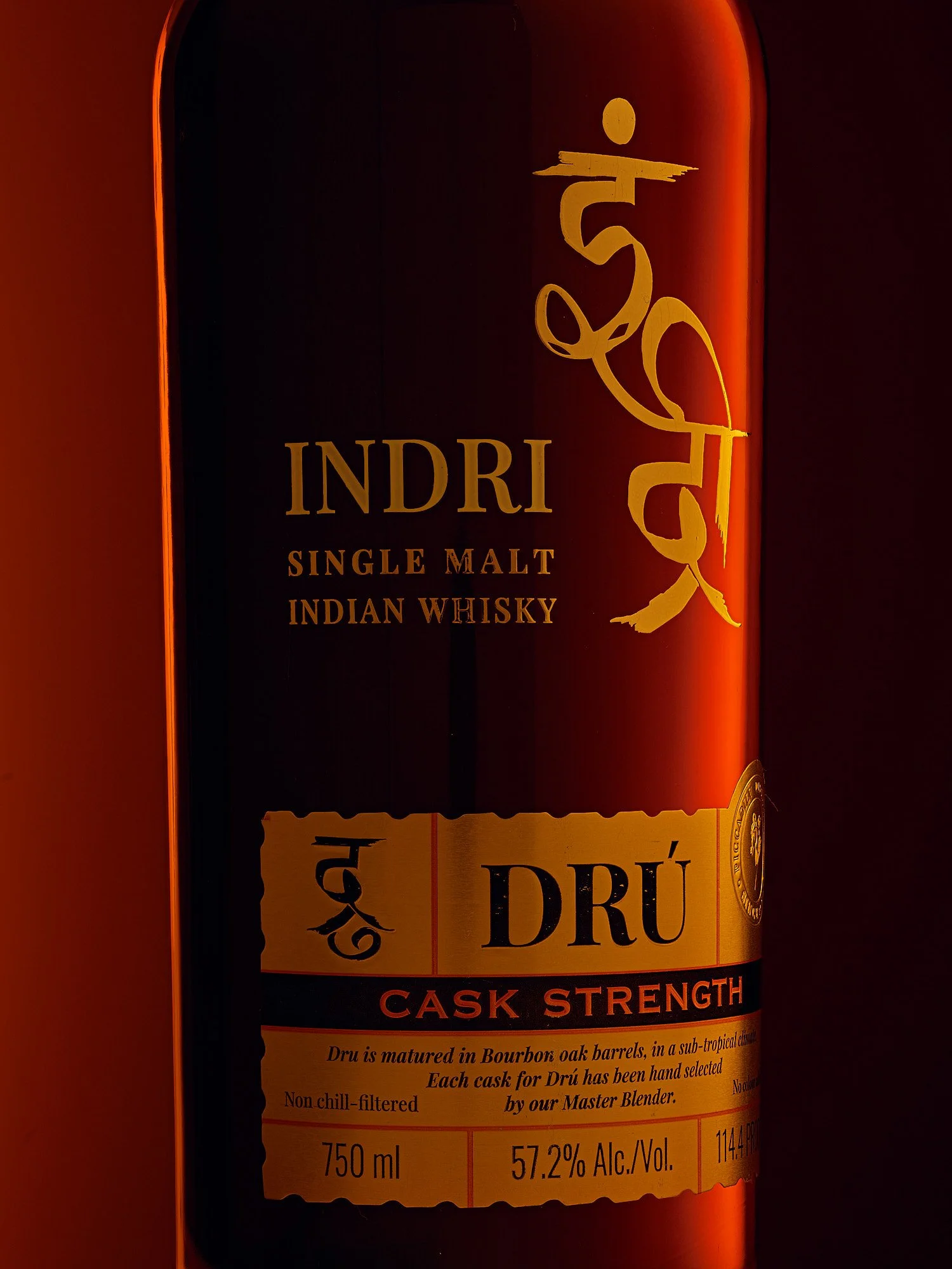 Spirits advertising photography by Dhanraj Emanuel — Indri Single Malt Indian Whisky Dūru Cask Strength bottle with dramatic dark red and gold label, shot for Piccadily Distilleries. Premium spirits photographer working nationally for beverage brands