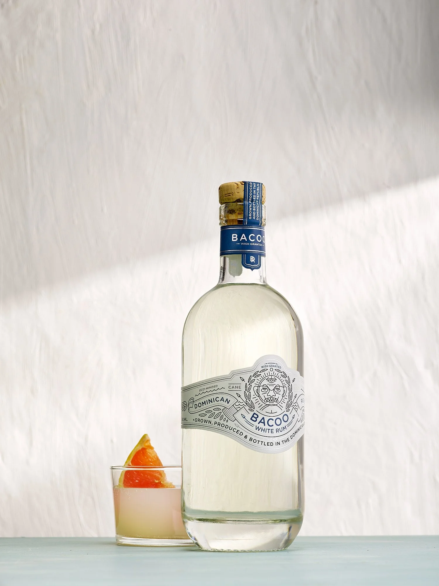 Beverage advertising photography by Dhanraj Emanuel — Bacoo White Rum bottle with garnished cocktail on white background. Commercial spirits and beverage photographer for brands and advertising agencies, available nationwide