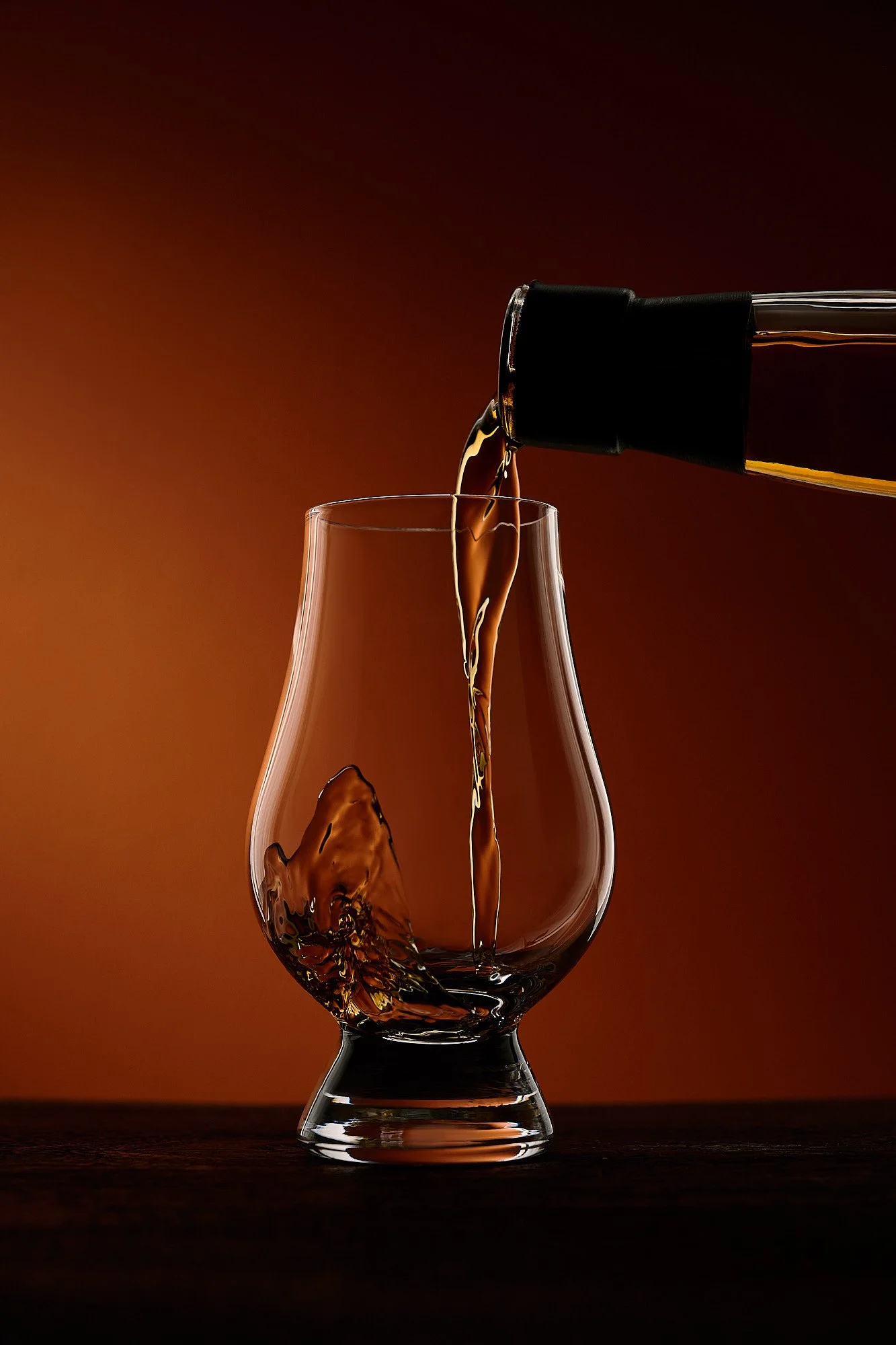Spirits advertising photography by Dhanraj Emanuel — dramatic dark-background whiskey poured into a Glencairn glass. Commercial beverage photographer for spirits brands and advertising agencies, available nationwide.