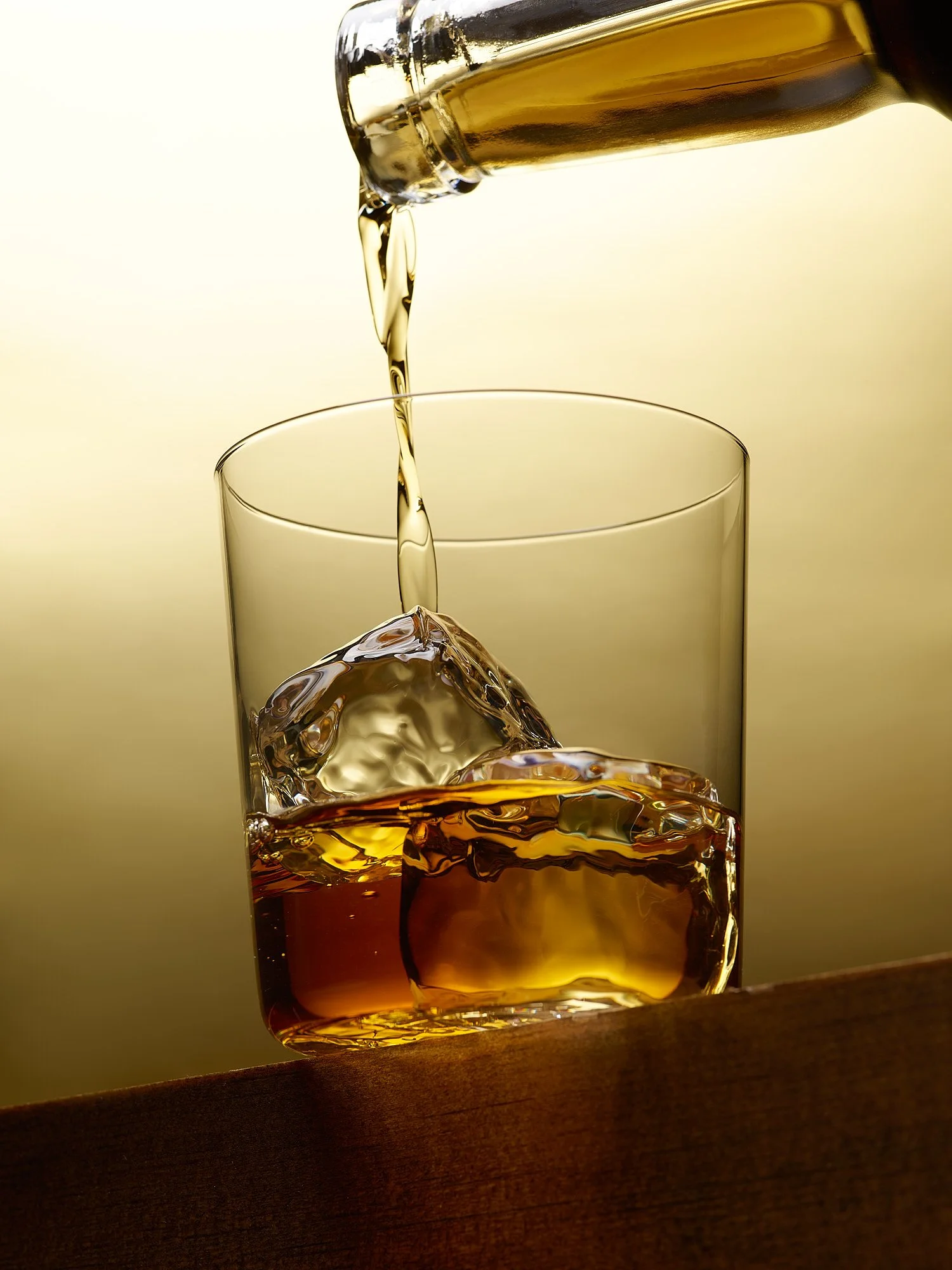 Beverage advertising photography by Dhanraj Emanuel — golden whiskey poured over ice, dramatic spirits photography for advertising and brand campaigns. Commercial drink photographer working nationally for spirits brands and agencies.