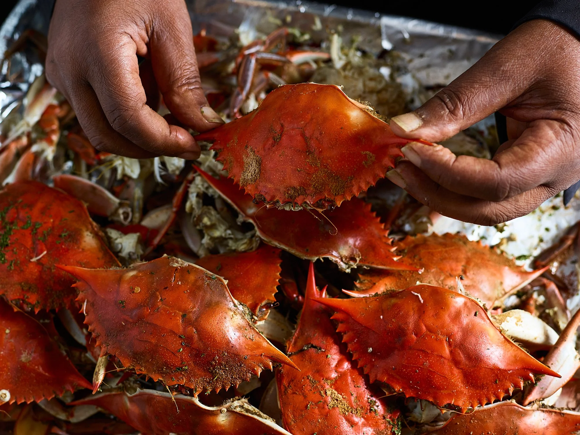 Food advertising photography by Dhanraj Emanuel — hands handling whole cooked crab, shot for Our State Magazine. Editorial and restaurant food photographer working nationally for magazines and hospitality brands.