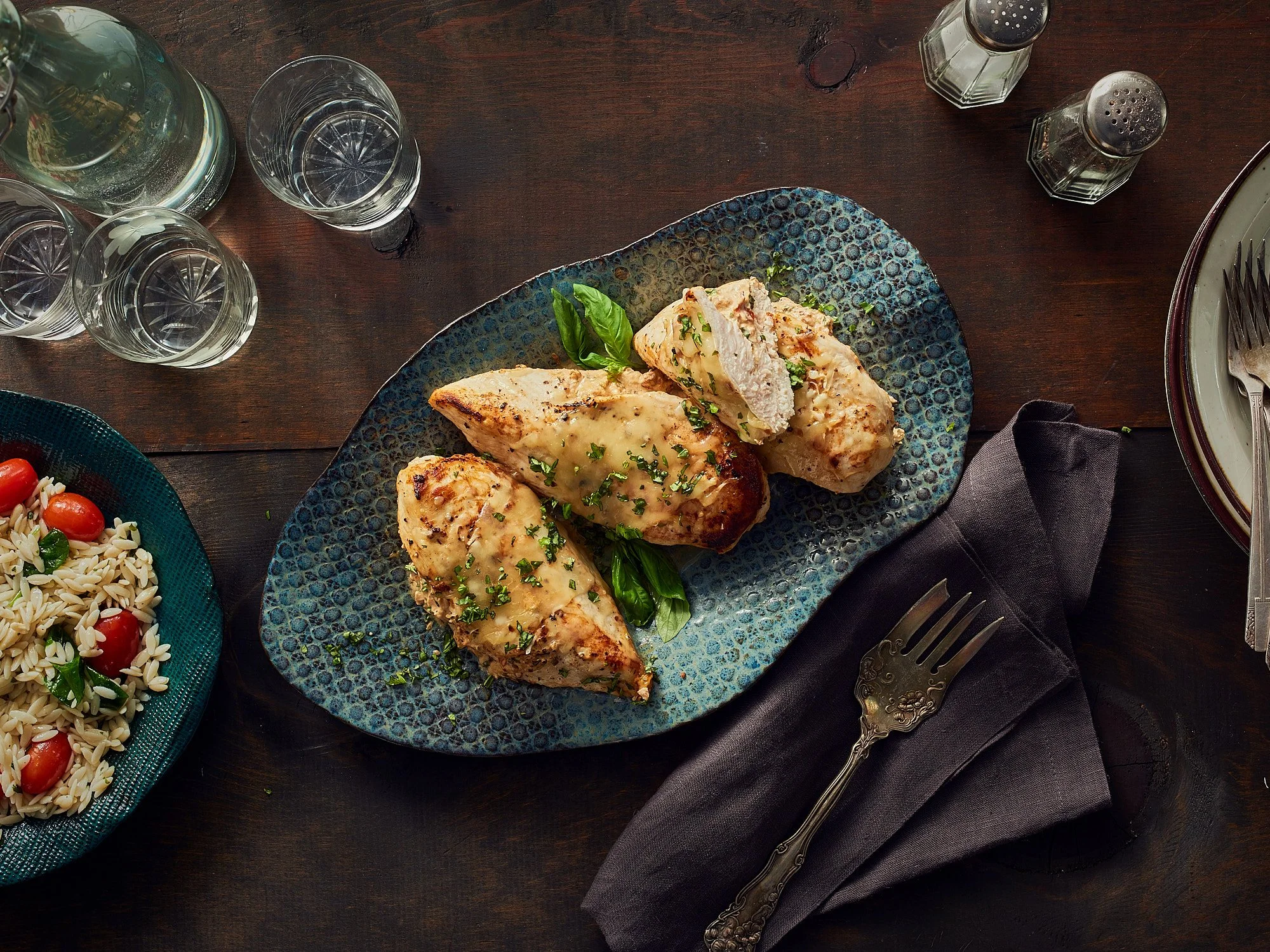 Commercial food photography by Dhanraj Emanuel — herb-garnished grilled chicken on decorative blue ceramic, shot for The Fresh Market. Food and beverage advertising photographer working nationally for agencies and brands.