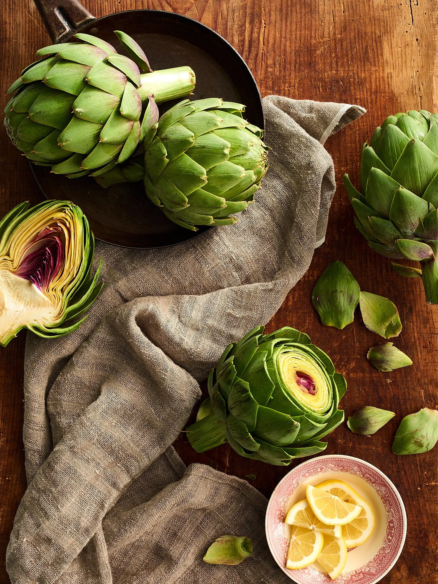 Food advertising photography by Dhanraj Emanuel — fresh artichokes with lemon on wooden surface, shot for The Fresh Market. Commercial food photographer based in Greensboro NC, working nationally for brands and agencies.