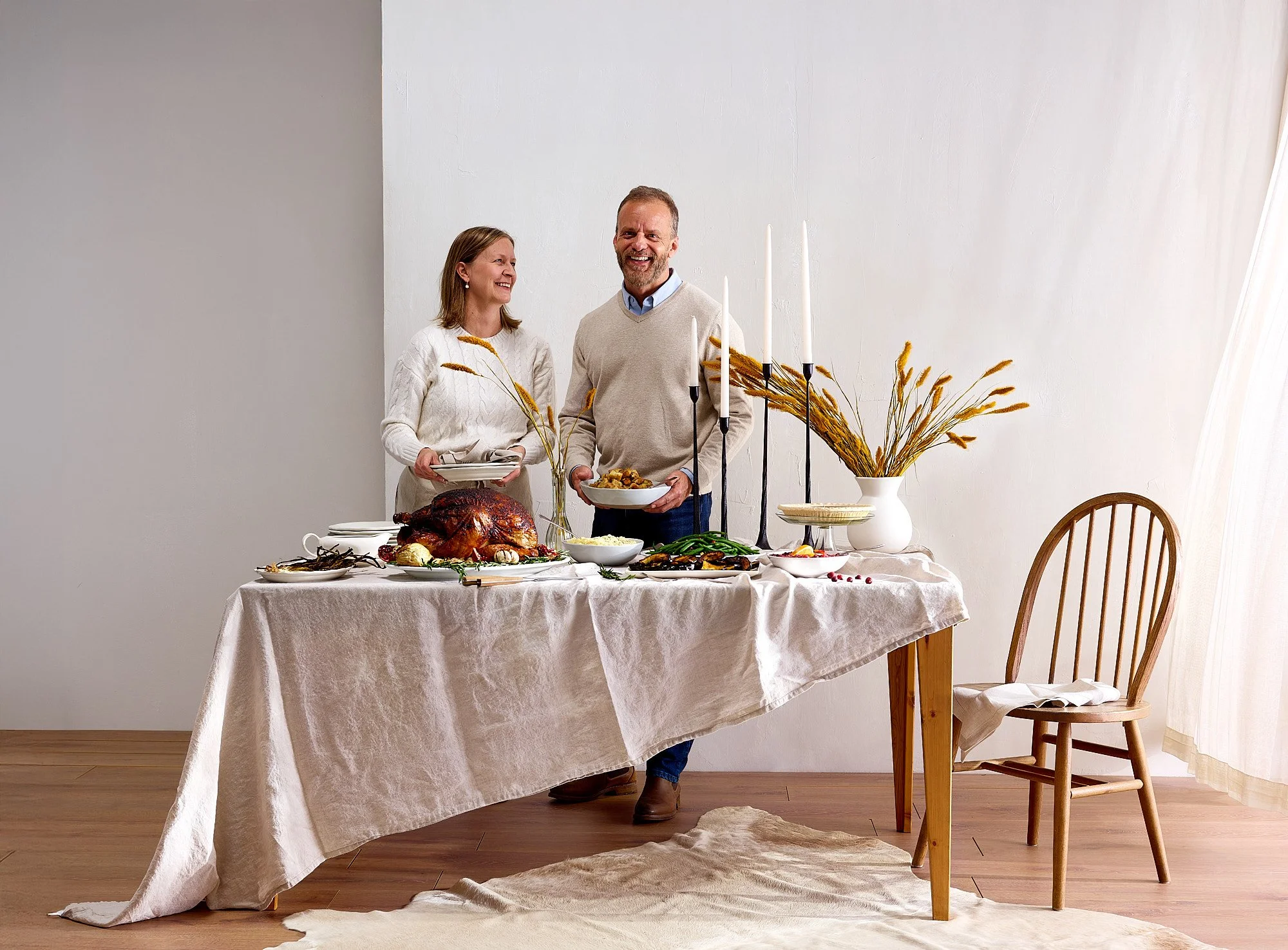 Lifestyle food photography by Dhanraj Emanuel — couple at decorated Thanksgiving dinner table with roasted turkey and fall decor, shot for The Fresh Market. Food and lifestyle photographer working nationally for CPG and grocery brands.