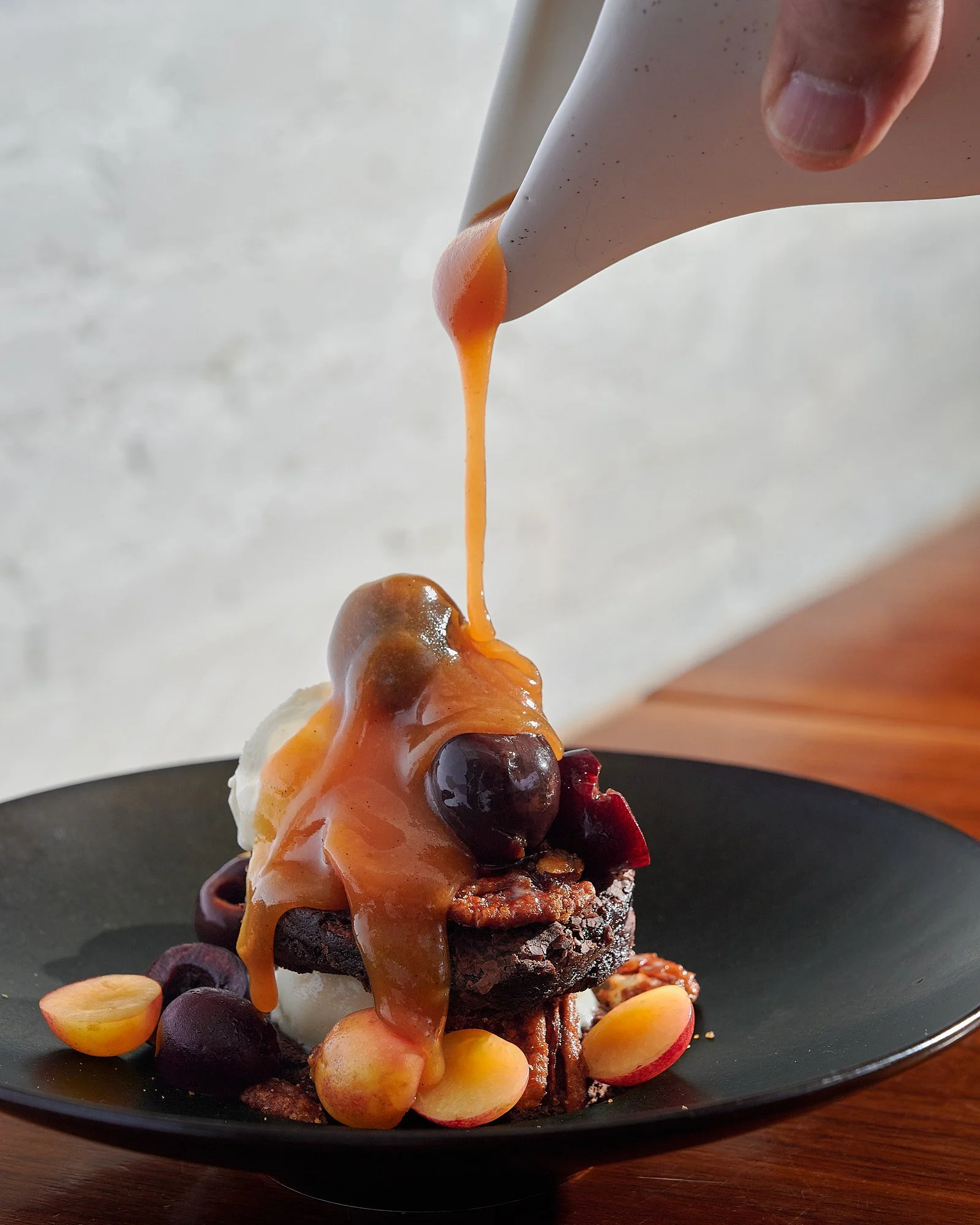 Caramel sauce pour dark dramatic food advertising photography for White and Wood by Dhanraj Emanuel, studio food photographer Greensboro NC