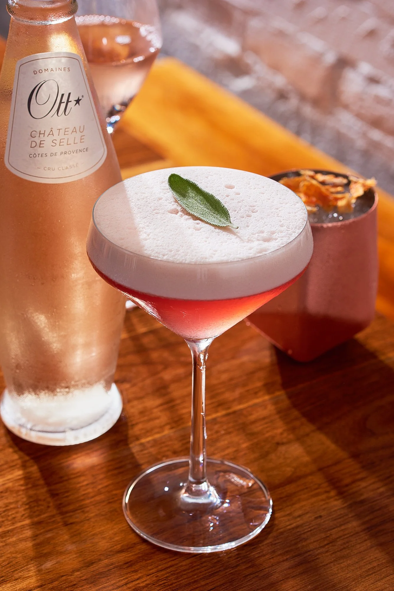 Beverage advertising photography by Dhanraj Emanuel — pink cocktail with foam and fresh garnish on a wooden surface. Commercial drink photographer for spirits brands, restaurants, and advertising agencies, available nationwide.