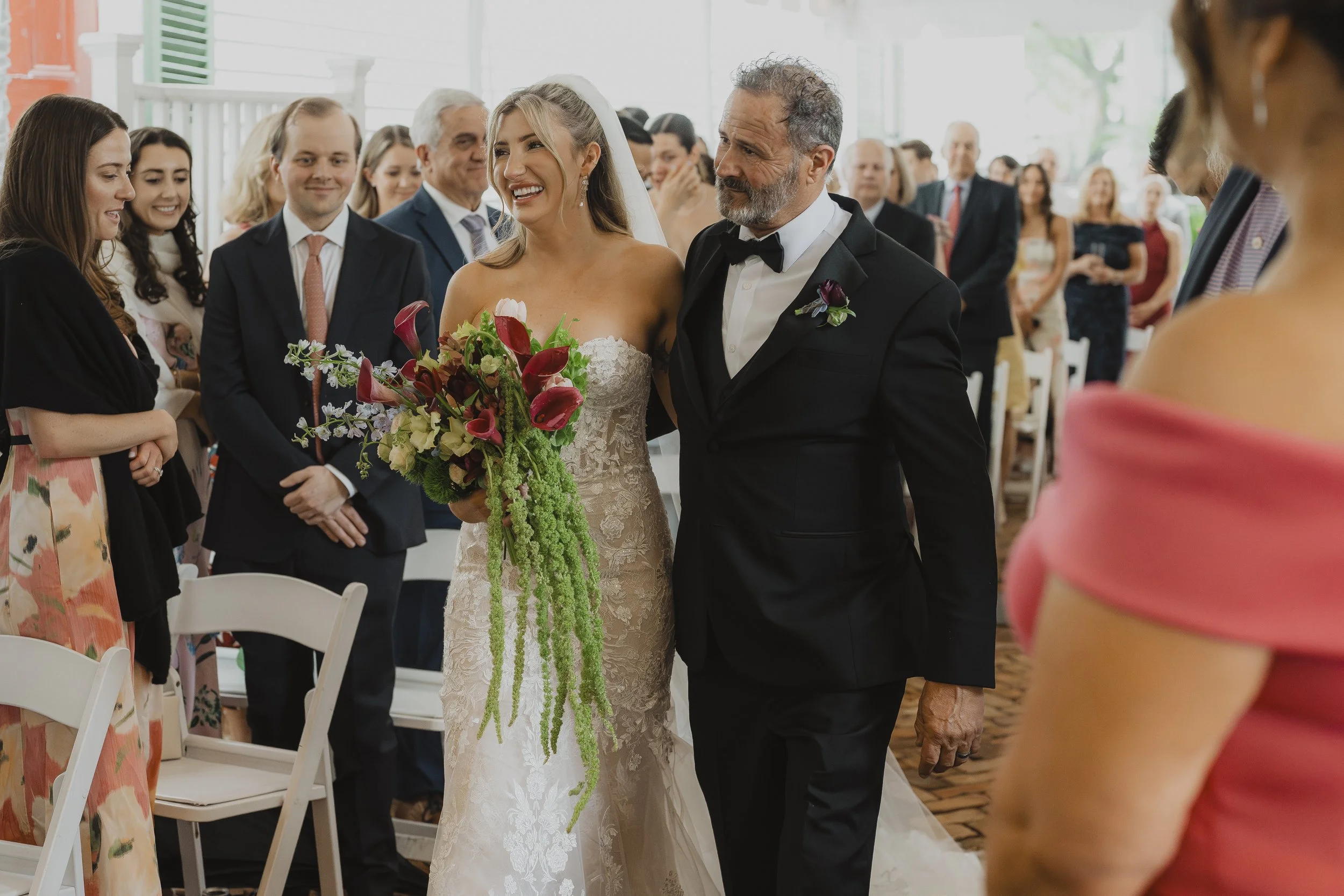 Bride walks down the aisle with her father as guests watch.