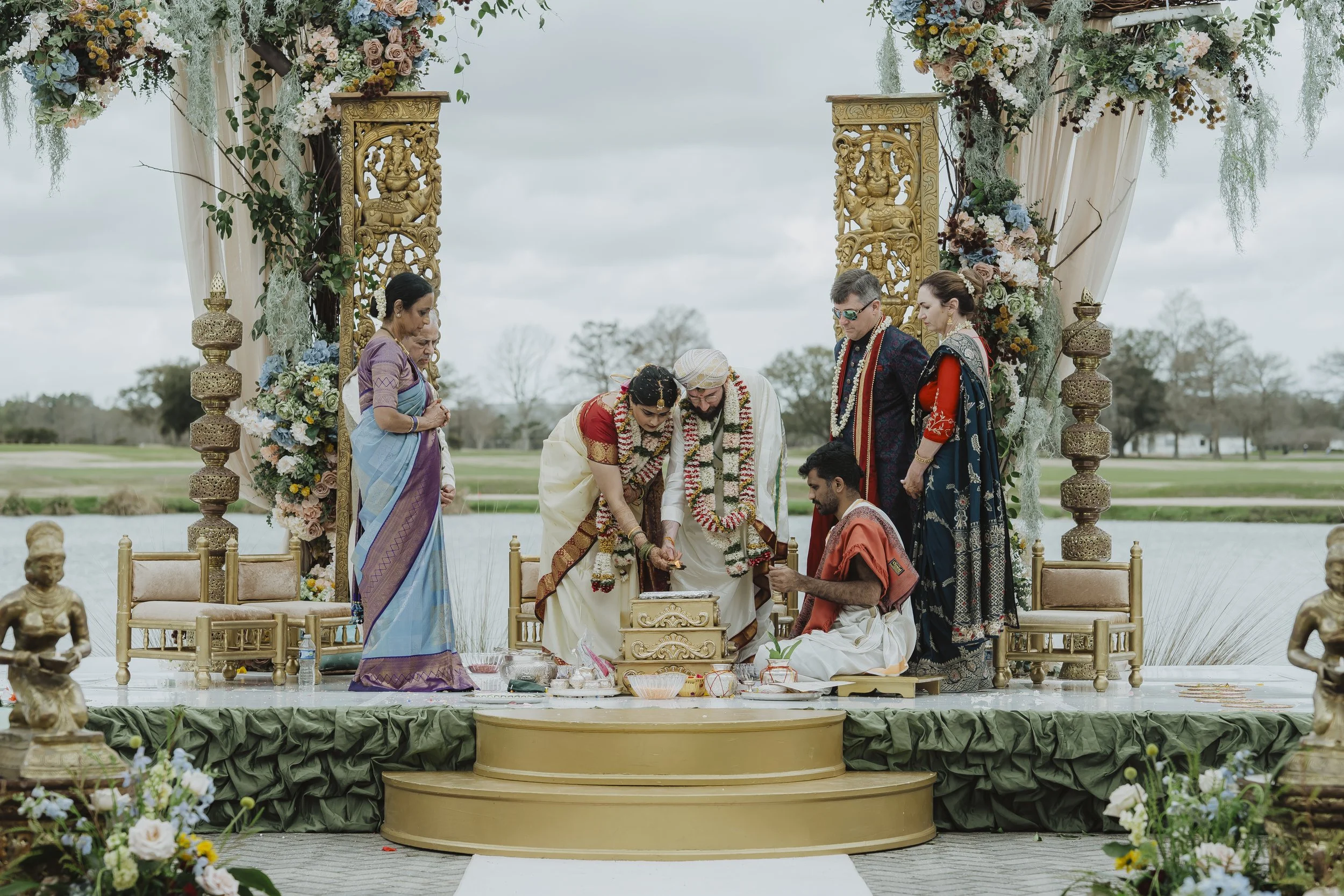 Couple participates in a colorful outdoor Hindu wedding ceremony beneath a decorated mandap.