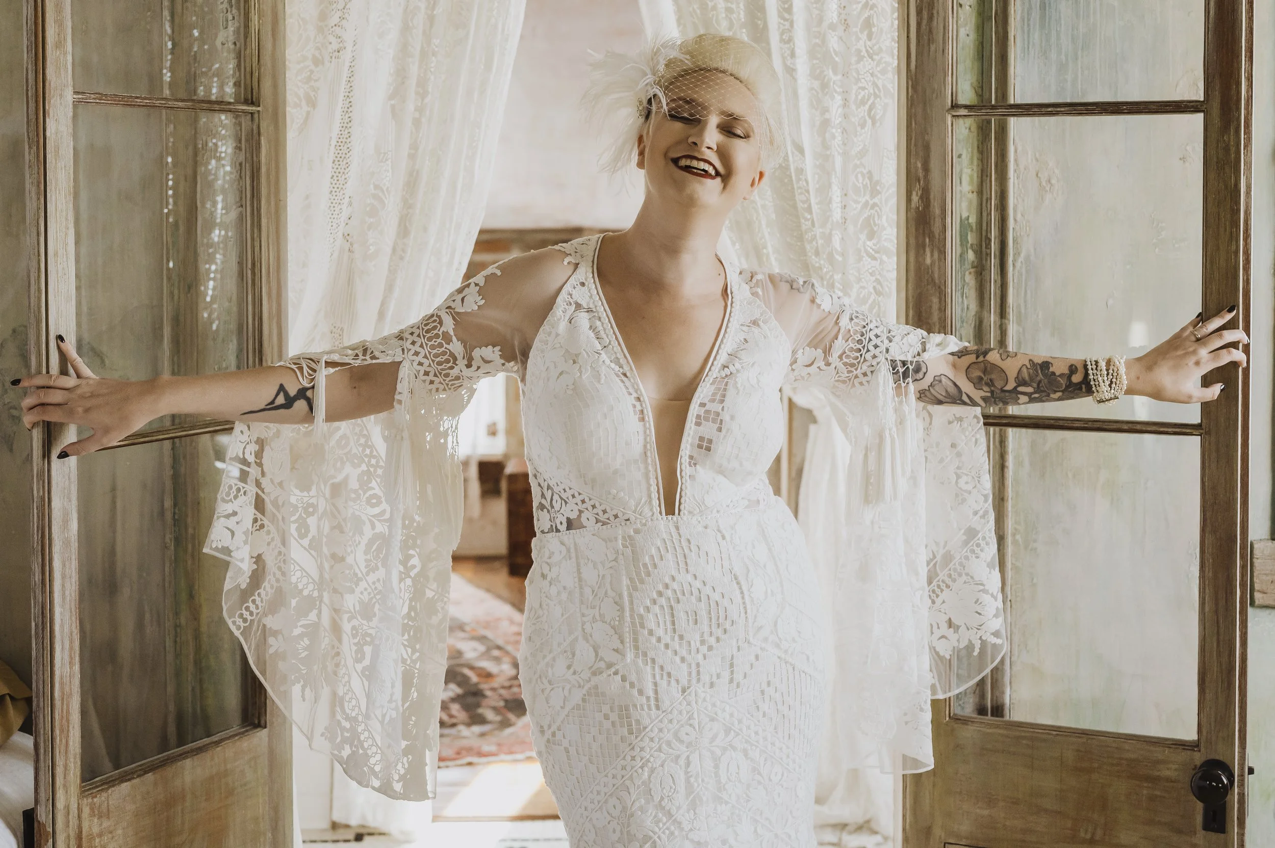 Bride standing in her wedding dress beside a sunlit window