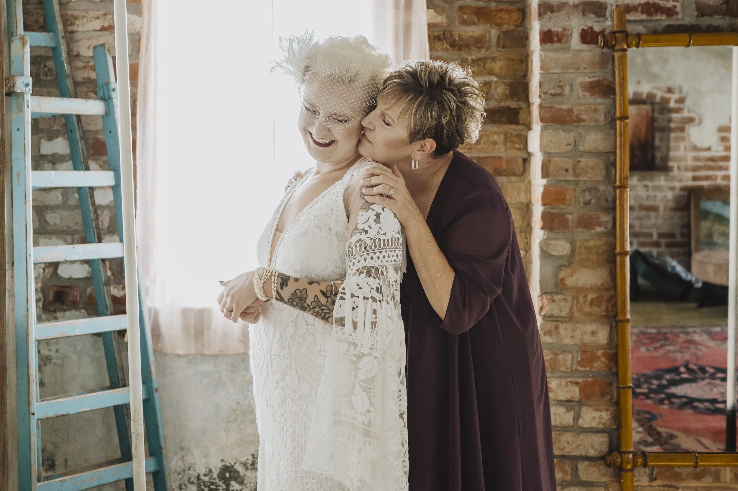 Bride sharing a hug with a family member while getting ready
