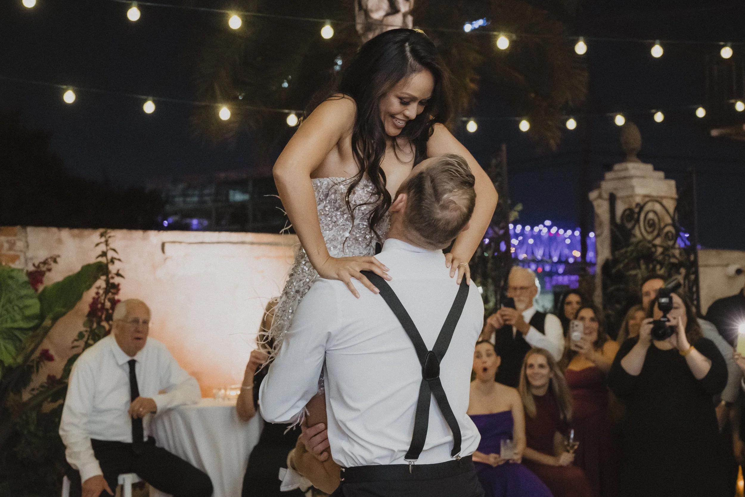 Newlyweds dancing beneath string lights during their wedding reception