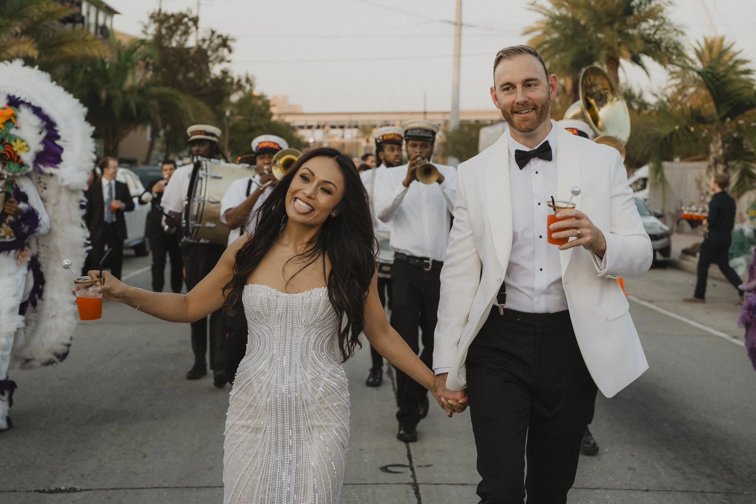 Newlyweds walking with drinks during their New Orleans second line