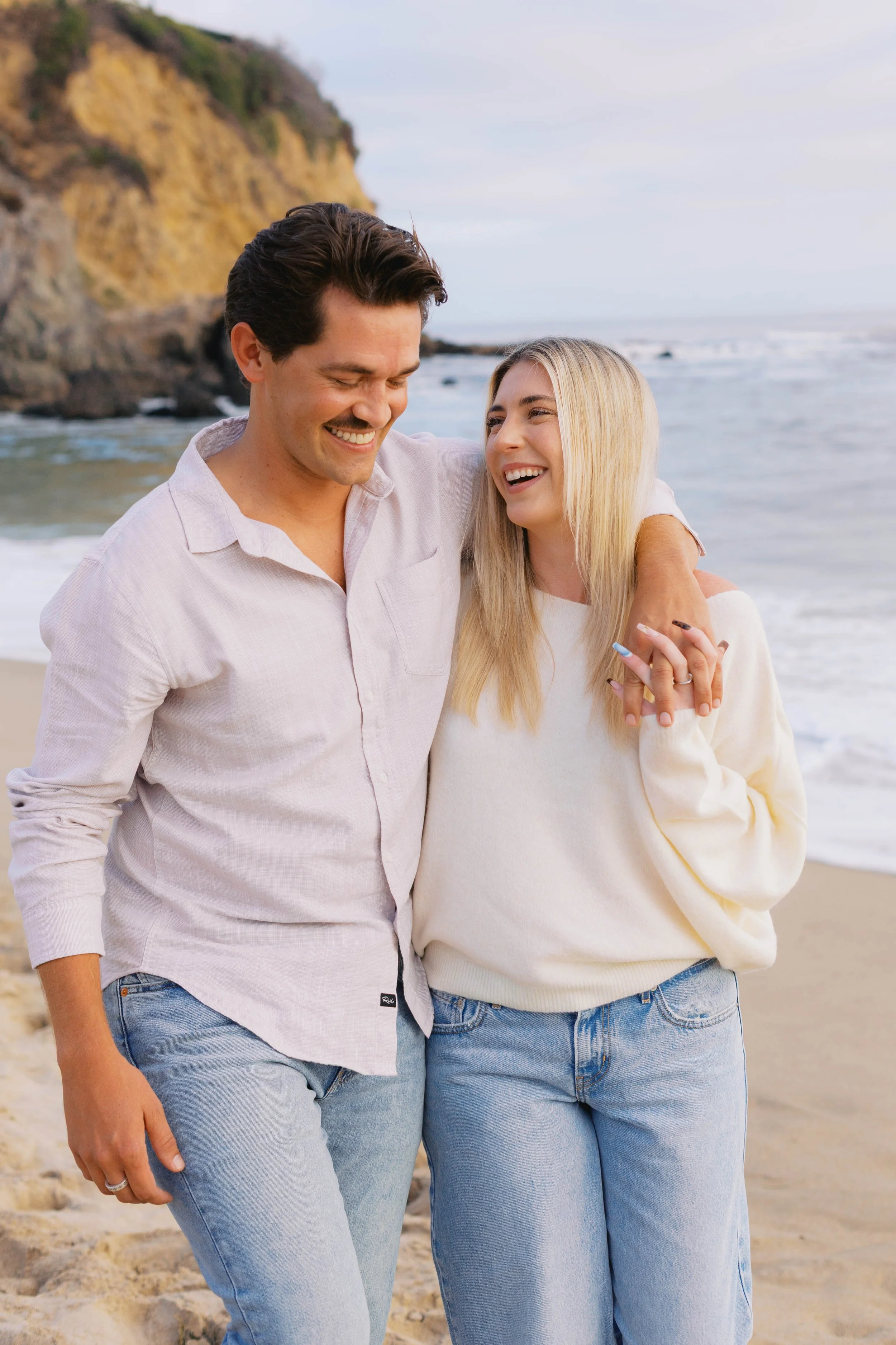 Candid engagement photo of a newly engaged couple walking together on the beach after their Laguna Beach proposal.