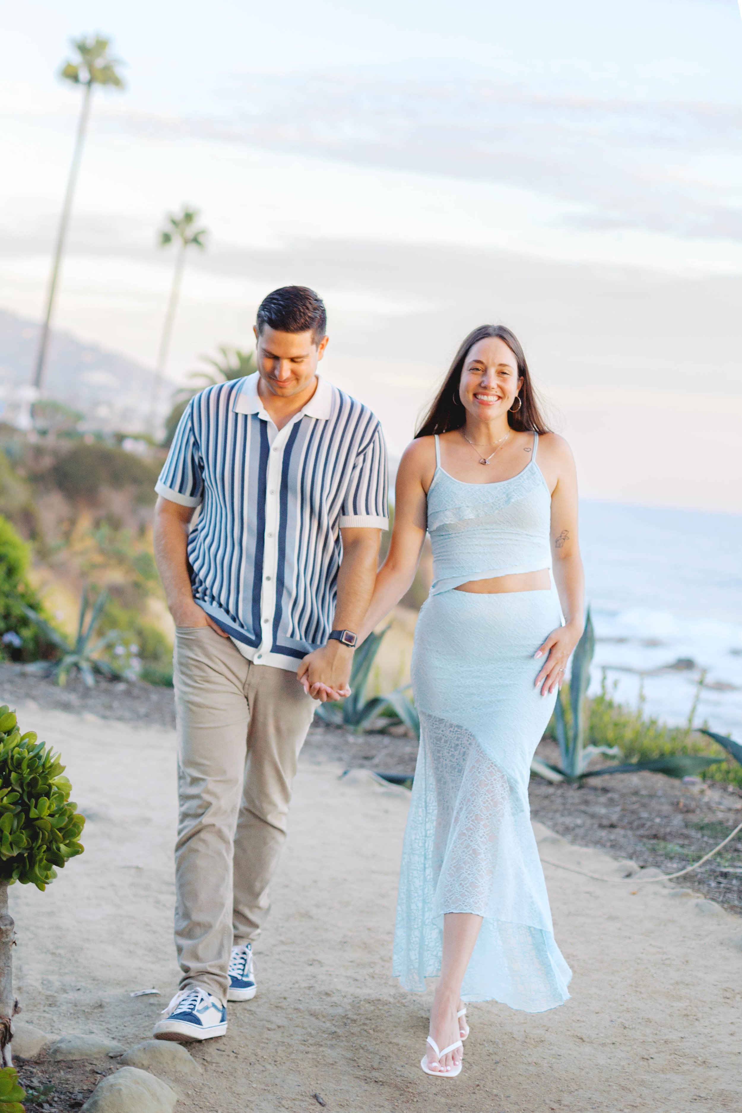 Andrew and Chloe candidly walking together with Treasure Island Beach in the background