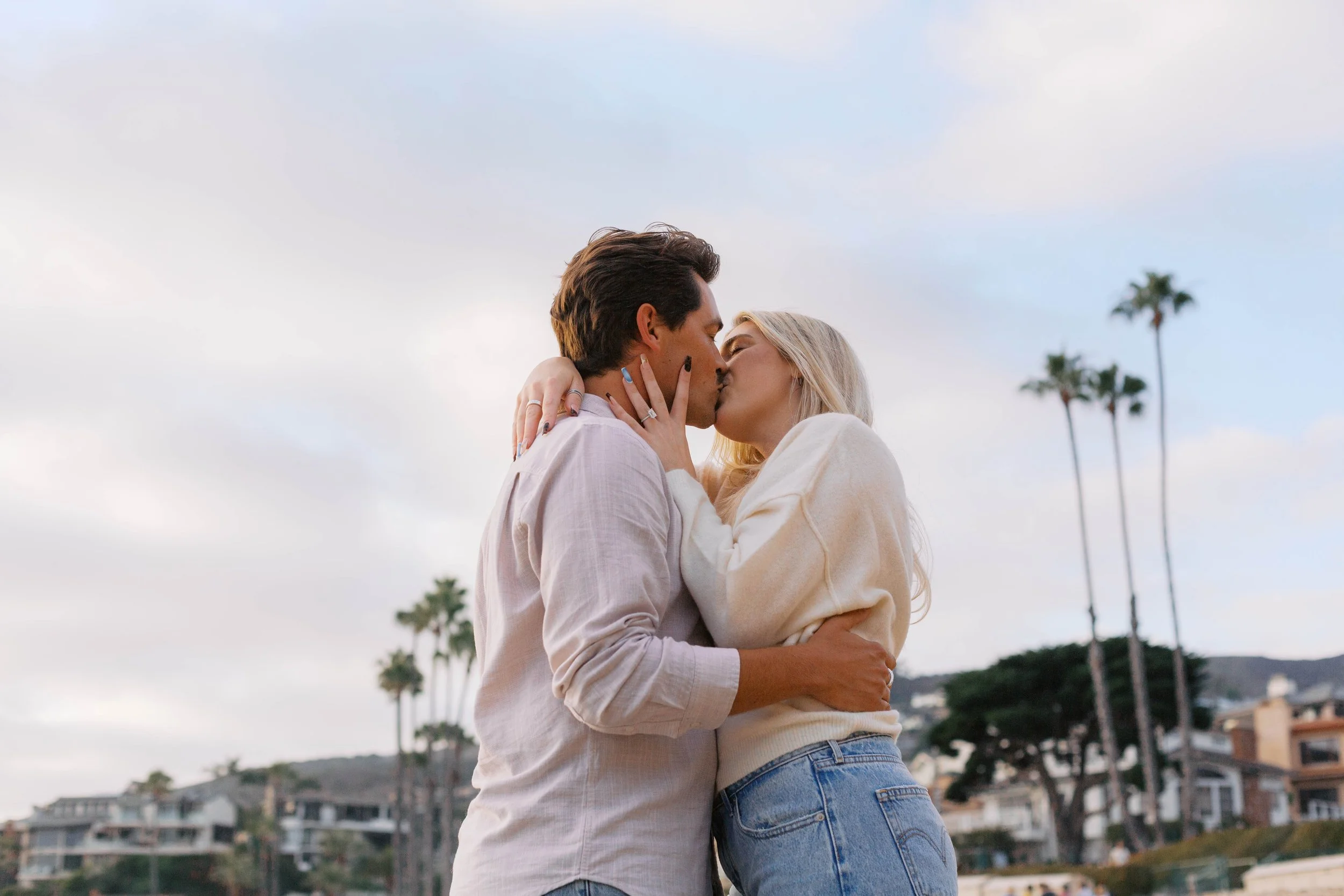 Romantic portrait of a newly engaged couple kissing after their Laguna Beach beach proposal.