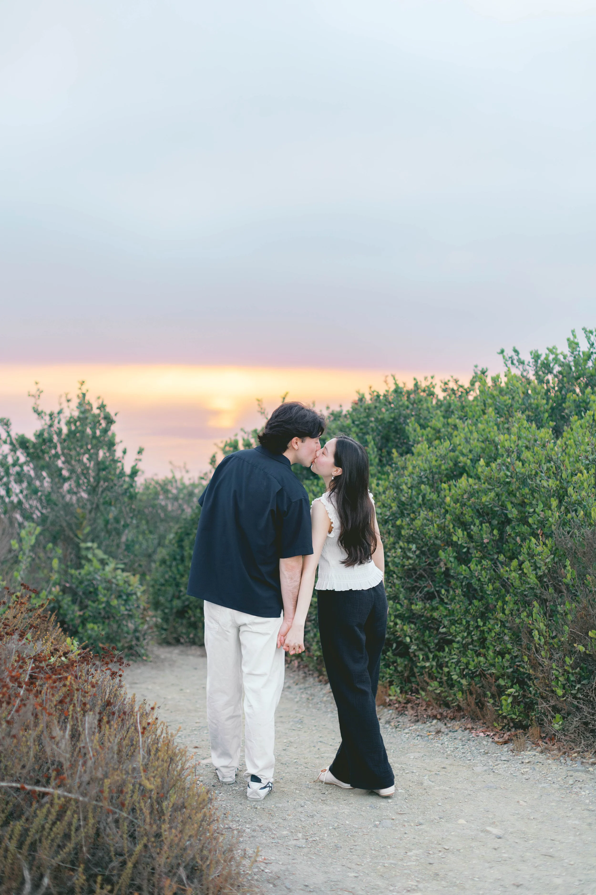 Newly engaged couple kissing during sunset portraits at Seaview Park.