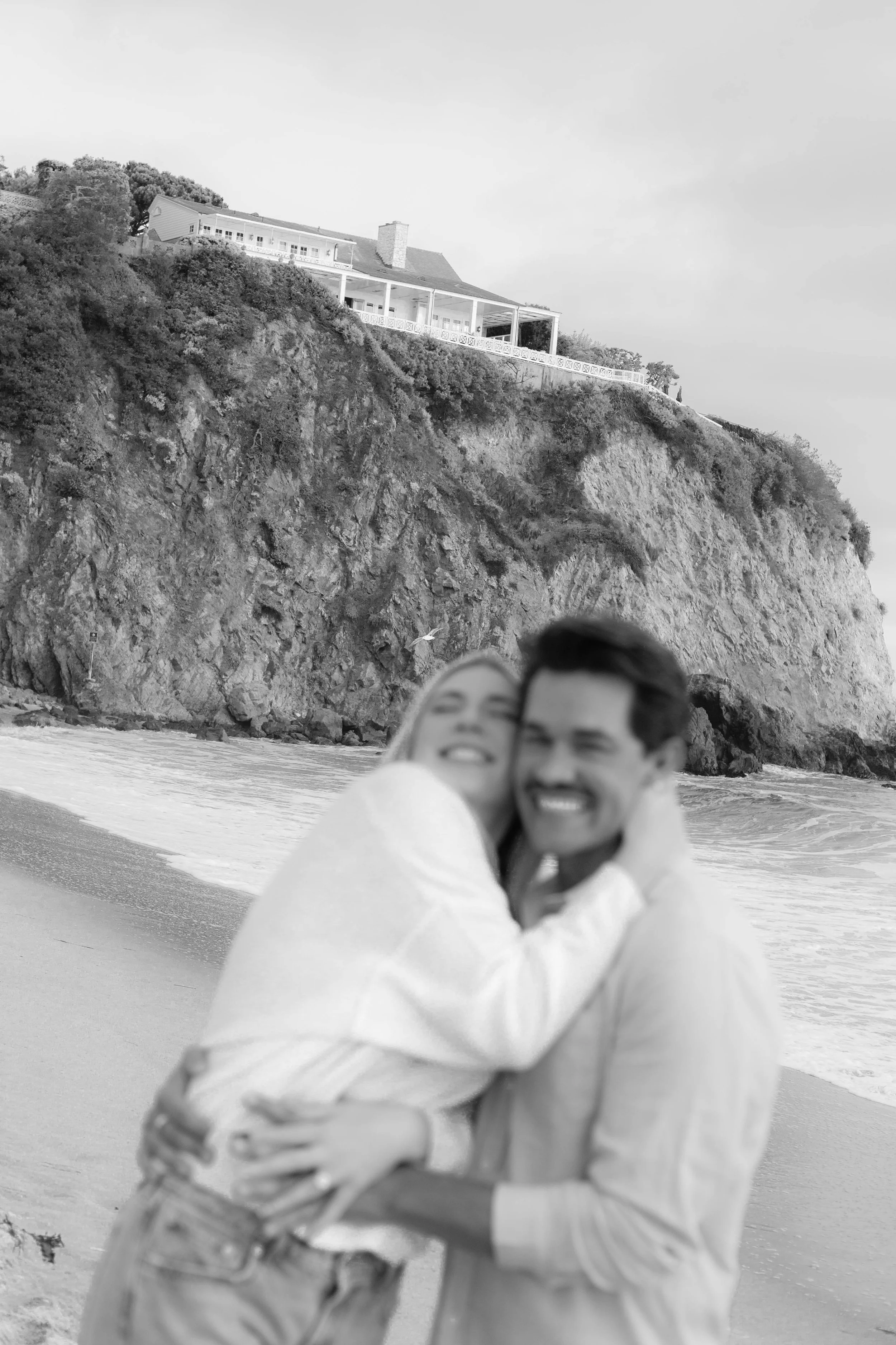 Black and white candid portrait of a newly engaged couple celebrating their proposal at Emerald Bay in Laguna Beach.
