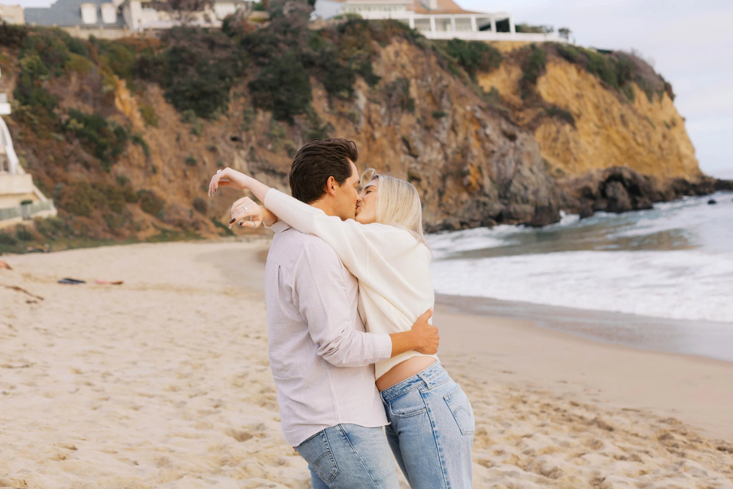 Newly engaged couple kissing on the beach after their romantic Emerald Bay proposal in Laguna Beach.