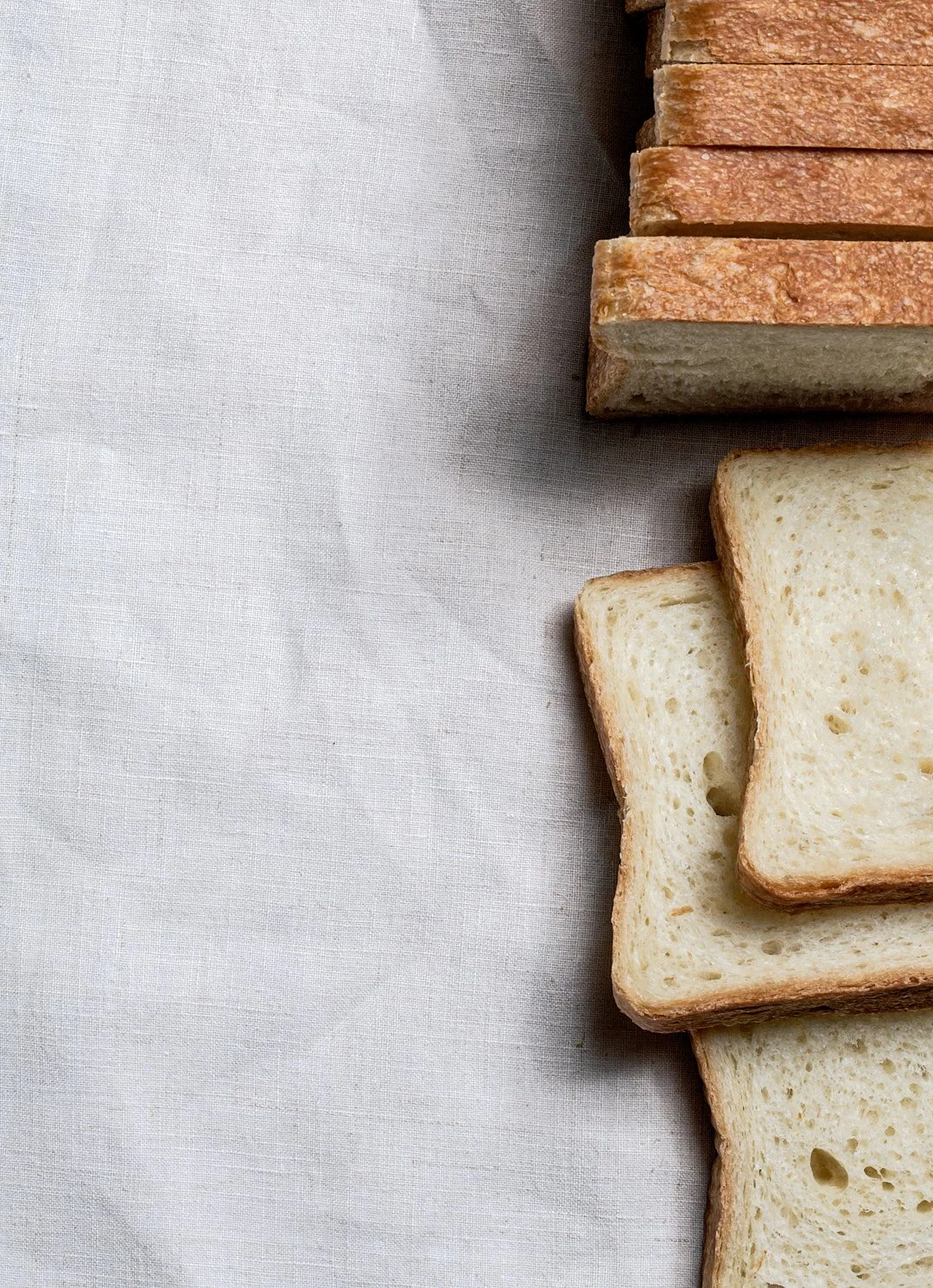 Slices of white bread arranged on a light-colored fabric surface.