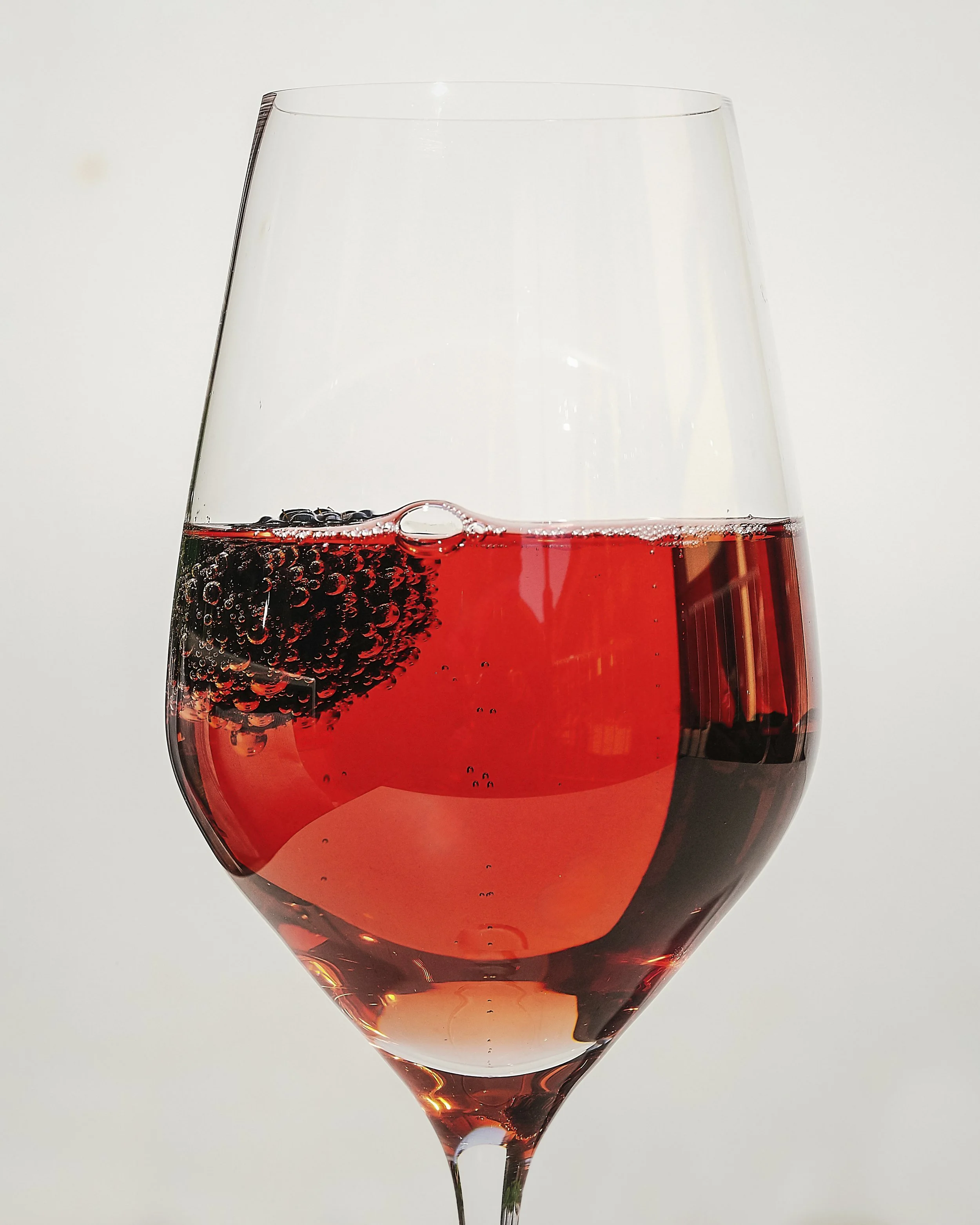 A glass of pink sparkling wine with blackberries inside.