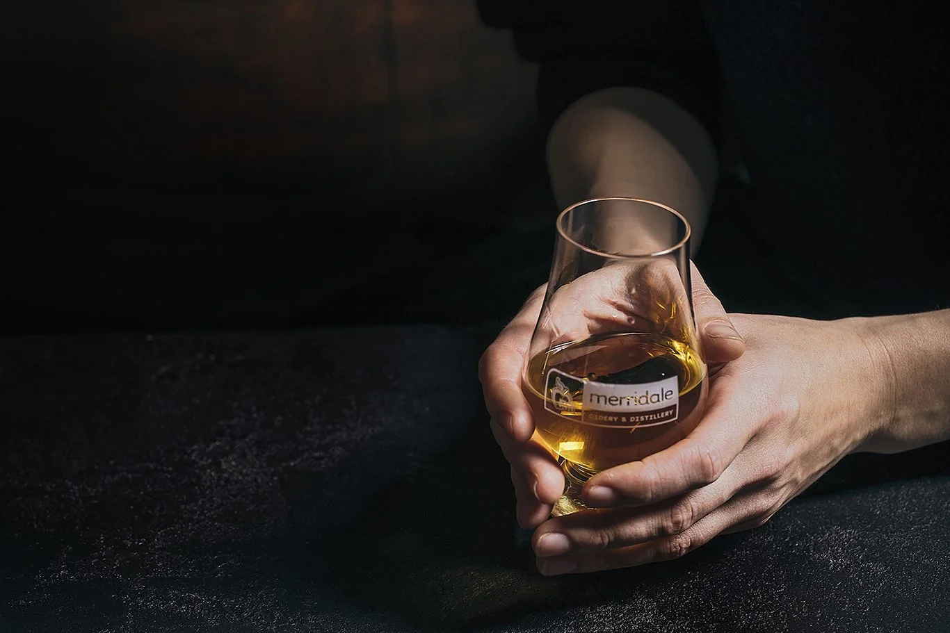 hand holding a glass of whiskey on a back background
