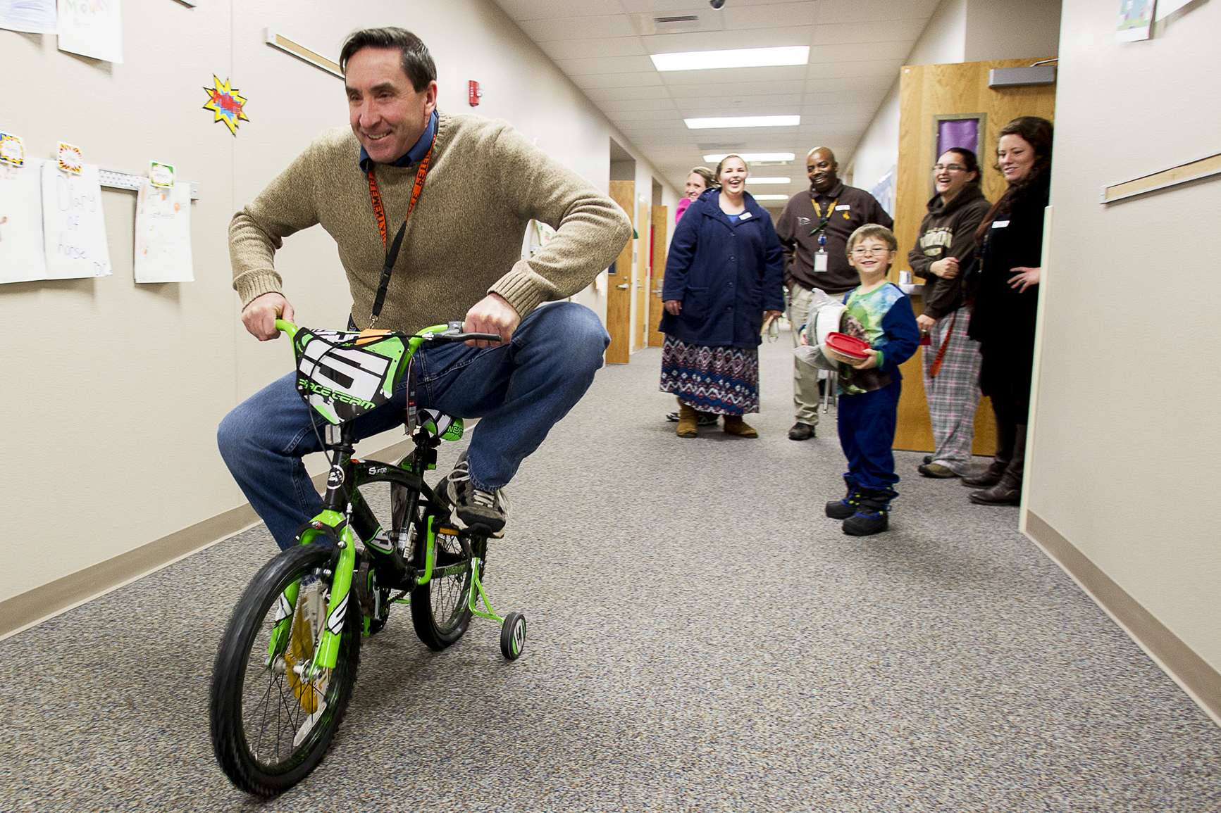 Lakeview principal Dale Petersen rides Zeke Williams's new bike down the hallway on December 22. The bike was donated to Williams by the YES House who worked with local businesses to give away 74 new bikes to children around Gillette.