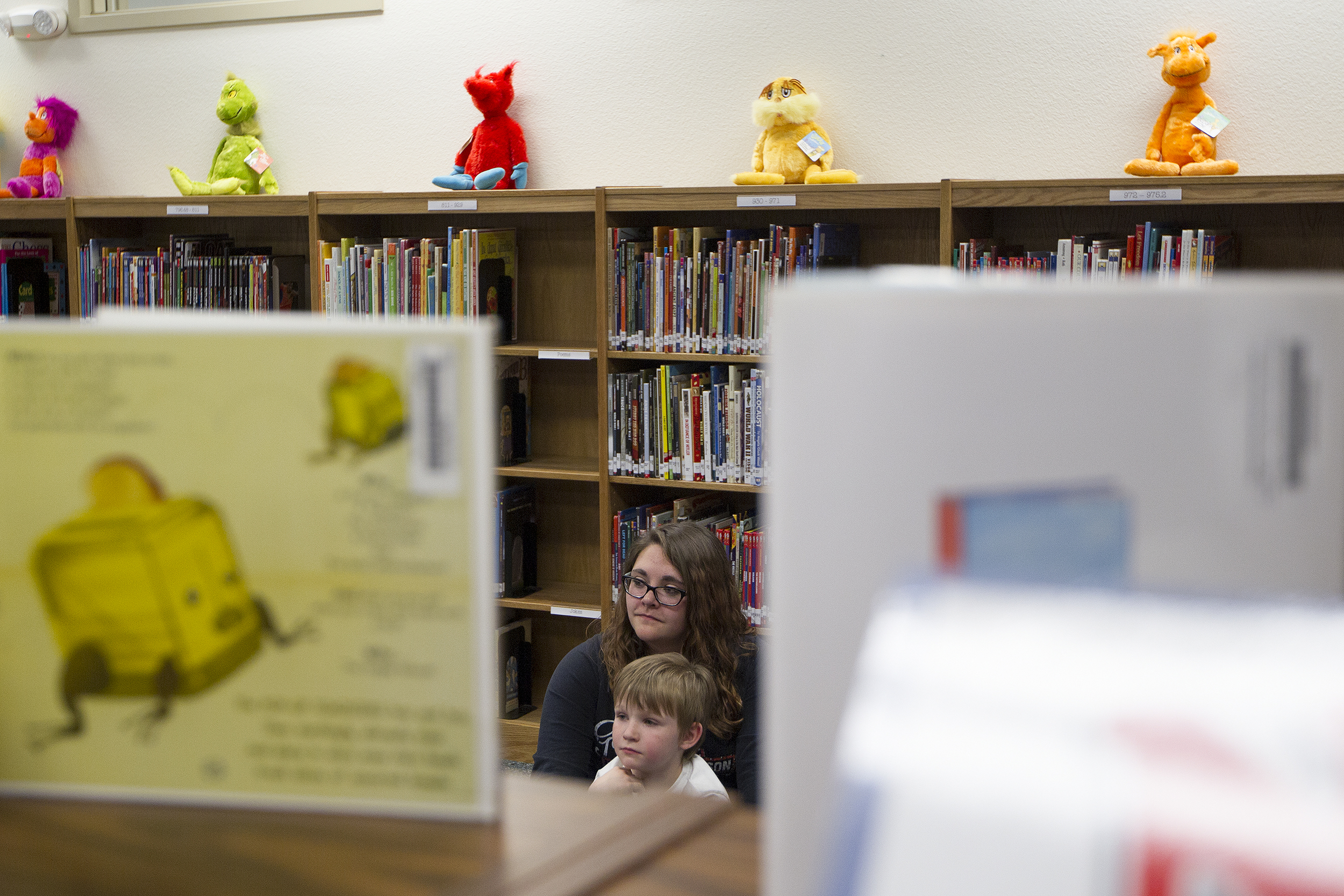 Kinsley Switzer, 14, and her brother Harlen Serrano, 5, listen to Cloud Peak Energy's Luke Malyurek read a book during Eat, Read, Grow Tuesday night at Wagonwheel Elementary School. Eat, Read, Grow is a program rotating around different schools where volunteers visit with kids, read to them, and the kids and get to take home a new book and a bag of groceries.