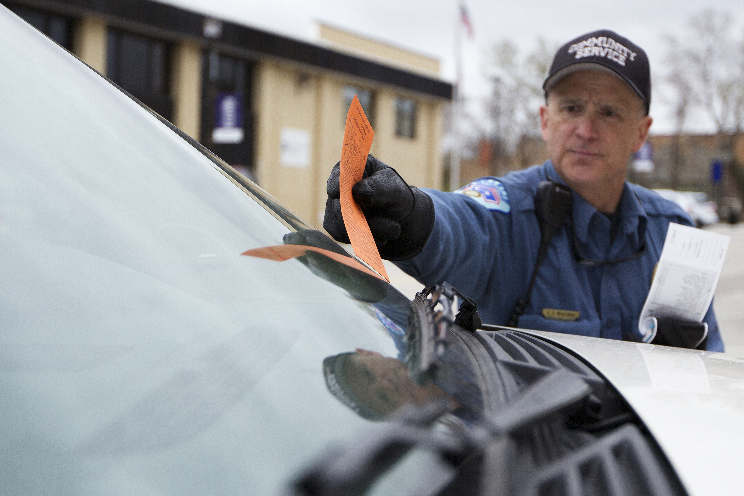 Gillette Community Service Officer Steve Wageman places a parking ticket on the windshield of a car on Gillette Avenue Tuesday afternoon. The city is hoping to cut between $450,000 and $500,000 by only filling two of the currently, or soon to be, open positions in the department.