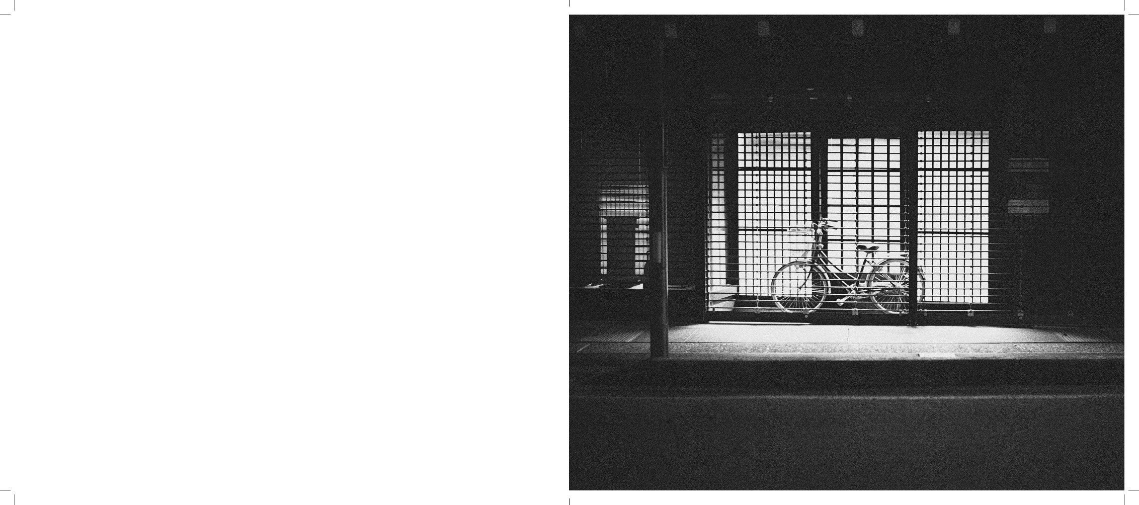 Bicycle parked inside a room with large window panes and a grid-like design, casting bright light into the dark interior.