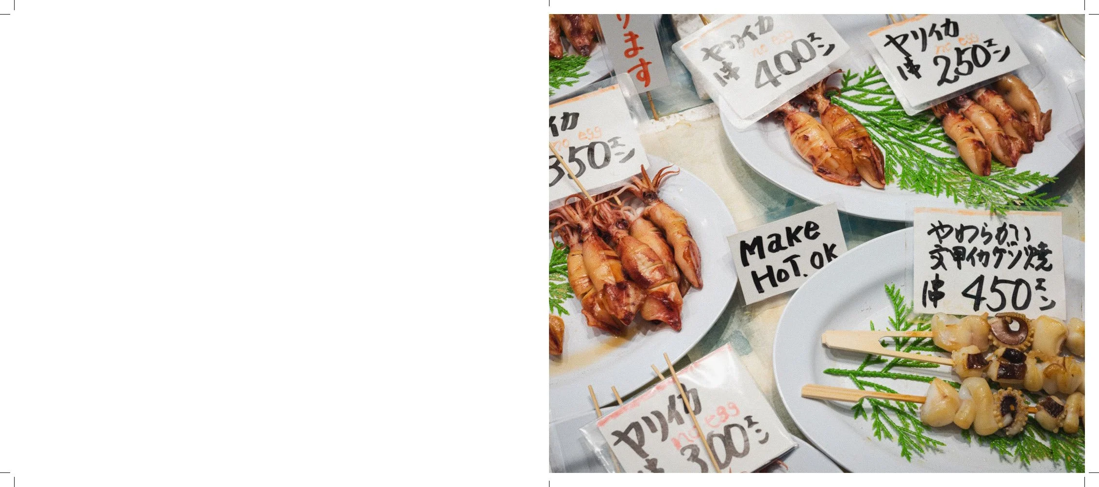 Fresh skewered seafood, including squid and other shellfish, displayed on white plates with handwritten price tags in Japanese yen, some with green garnish, at a seafood market in Japan.