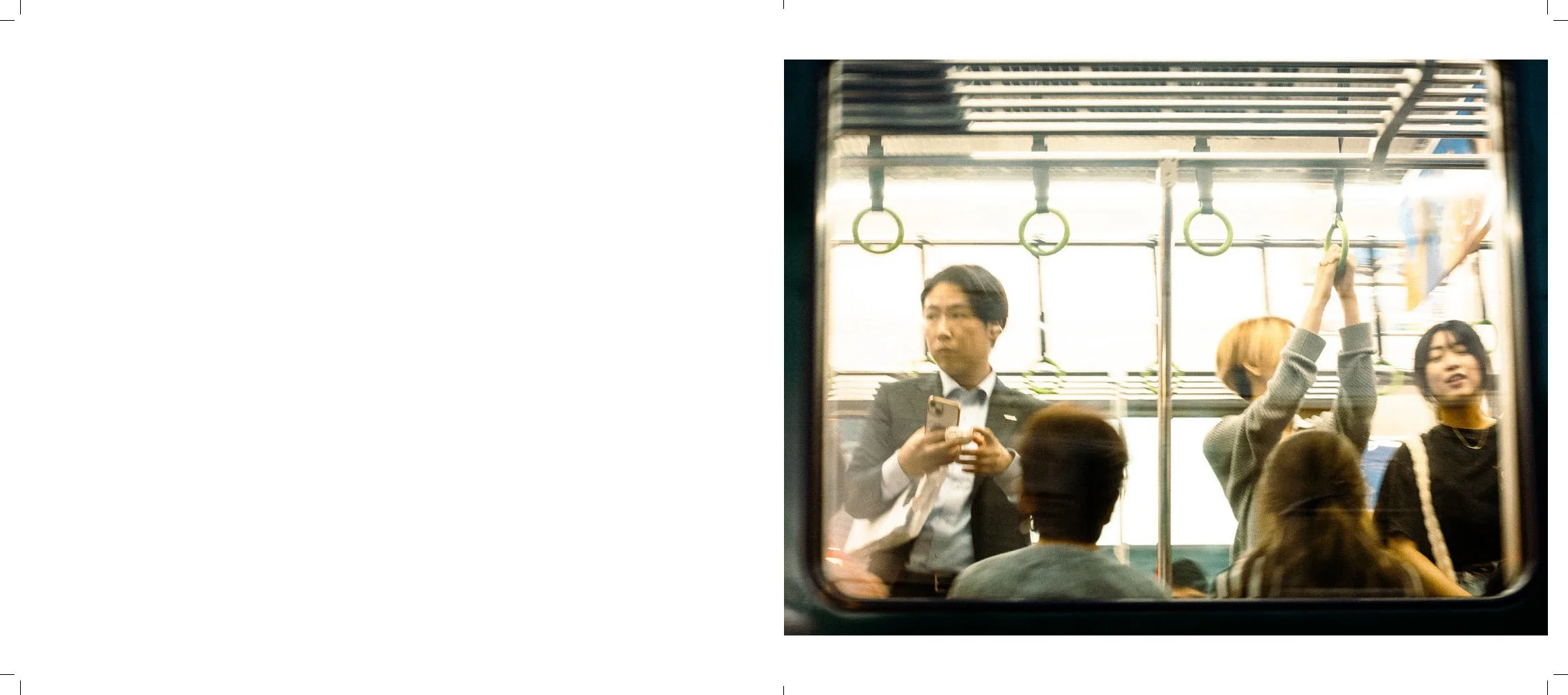 People standing inside a subway train. One person is looking at their phone, and two others are reaching to hold onto the handrails.
