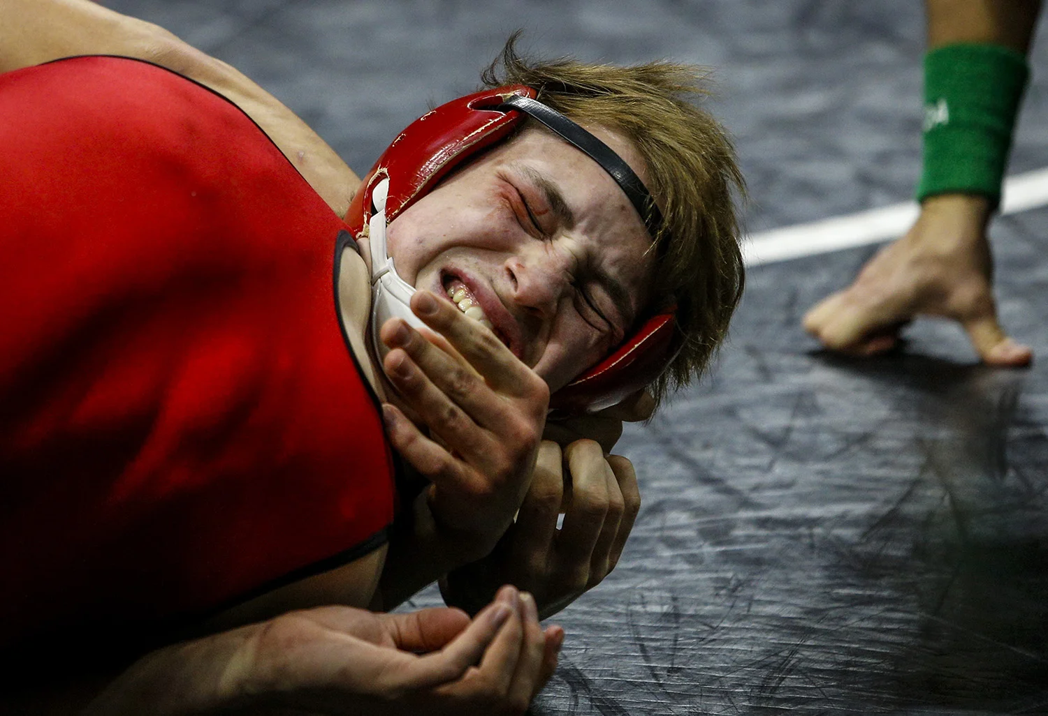 New Hampton's Noah Glaser grimaces as the hand of Assumption's Peter Laubenthal reaches for his chin during the semifinals of the 2017 IHSAA Dual Team Wrestling Tournament at Wells Fargo Arena in Des Moines, Iowa, on Wednesday, February 15, 2017. 