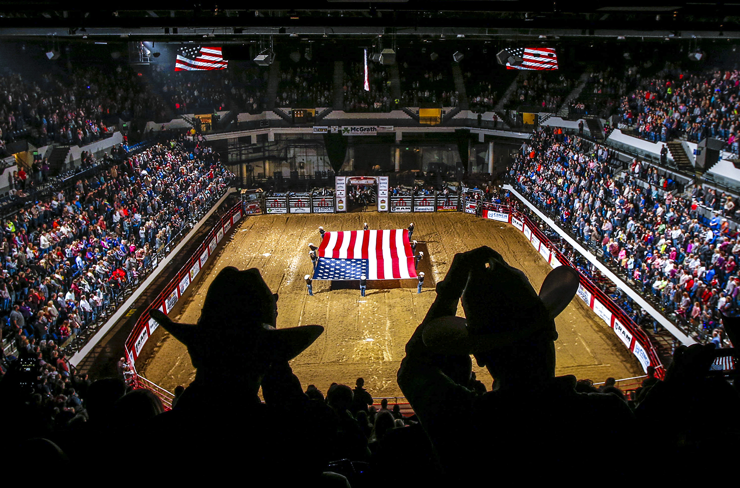 Two men remove their hats as the American flag is presented before the singing of the national anthem at the U.S. Cellular Center in Cedar Rapids on Friday, Jan. 29, 2016. The World's Toughest Rodeo makes a weekend stop in Cedar Rapids displaying bull riding, saddle bronc riding, bareback riding and a number of other events.