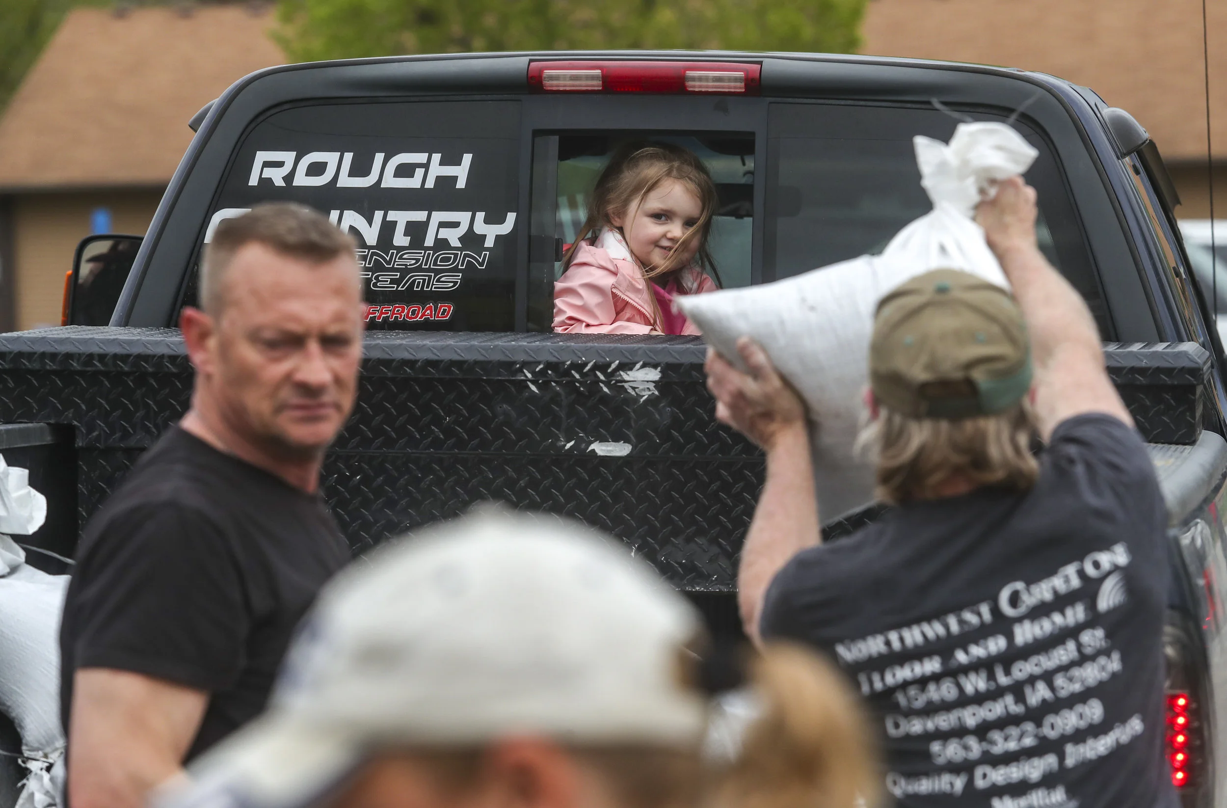 Maezie Sundwell, 3, of Buffalo watches as volunteers load her father’s pickup with sandbags to take down to homes fighting flooding in Buffalo, Thursday, May 2, 2019.