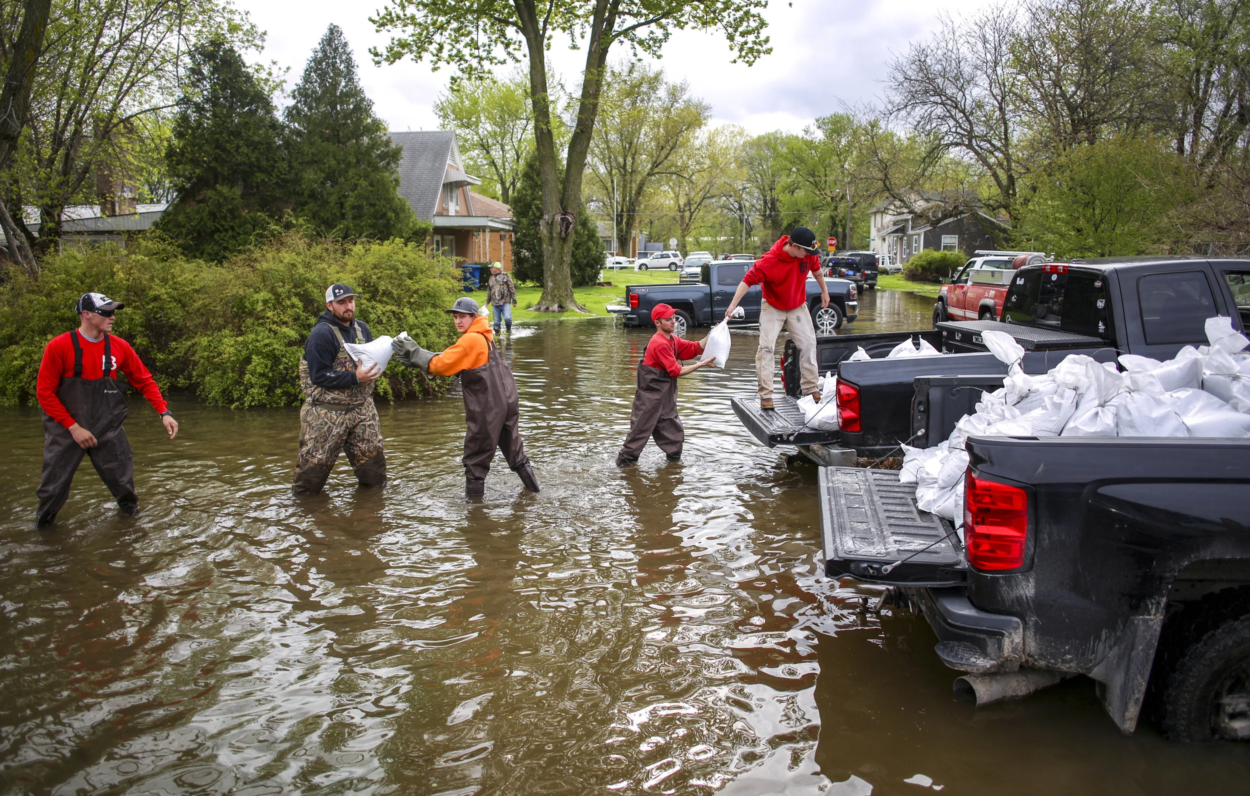A line of neighbors and volunteers load sandbags out of a truck into a boat to be taken into a flooded area of Front Street in Buffalo, Thursday, May 2, 2019.