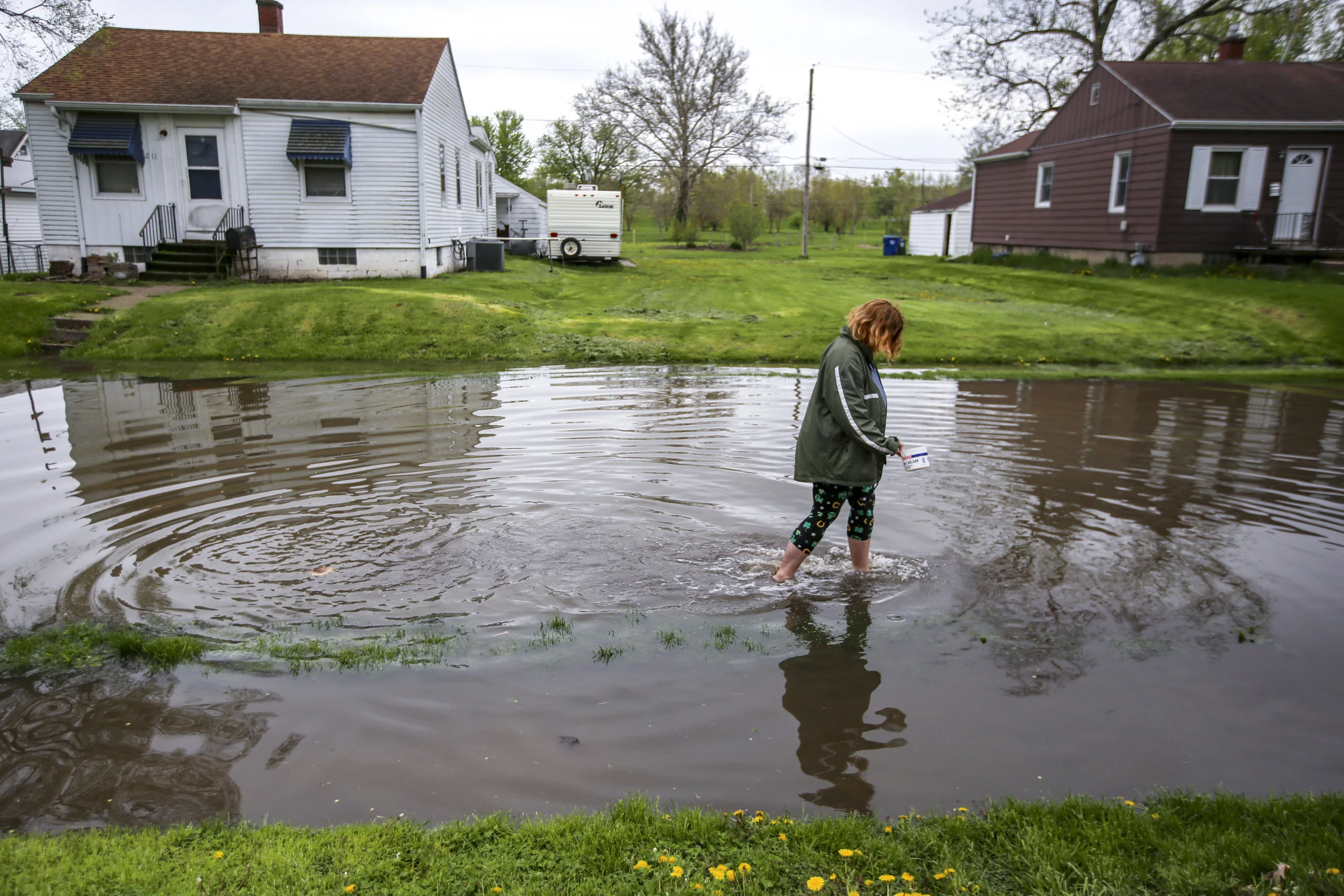 Heavenly Litty of Wilton walks out of the floodwaters on Sunnyside Avenue after retrieving litter that was floating down the block in the Garden Addition of Davenport, Wednesday, May 1, 2019.
