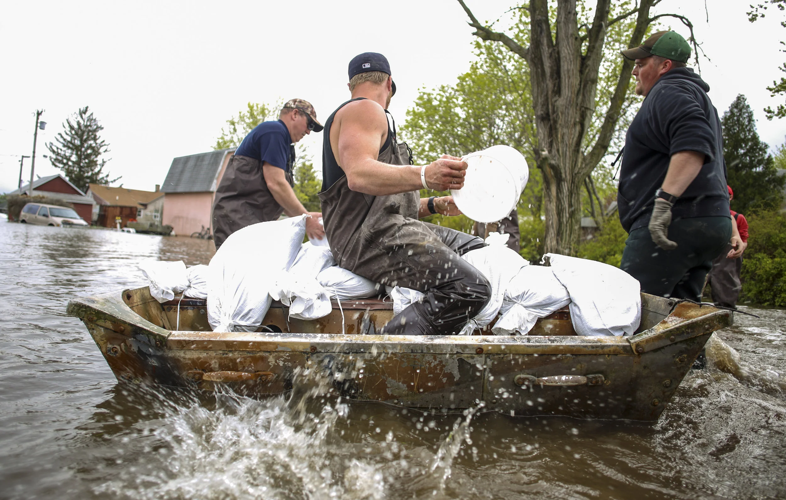 Zach Bowers of Buffalo bails out water from a boat as it is loaded with sandbags to go help a neighbor on Front Street in Buffalo, Thursday, May 2, 2019.