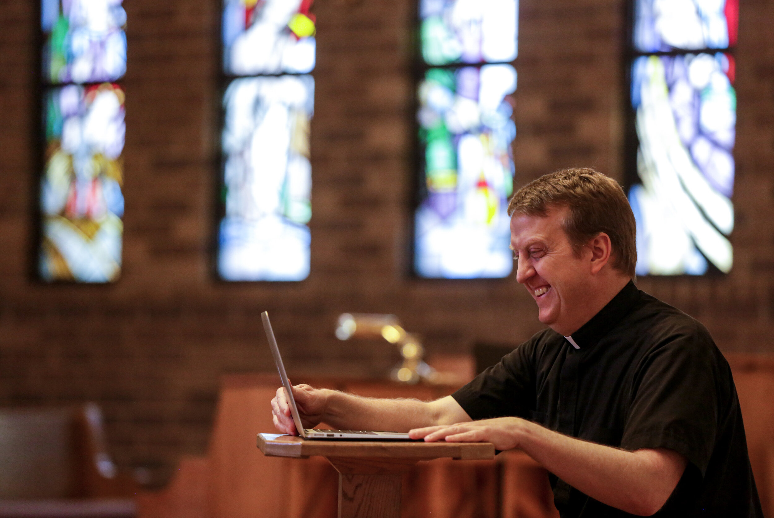  Rev. Mark Murphy gets his laptop ready to live-stream mass at St. Jude’s Catholic Church in Cedar Rapids, Iowa, on Saturday. St. Jude hasn’t previously relied on recording or streaming mass, so Murphy improvised by placing his laptop on a small tabl
