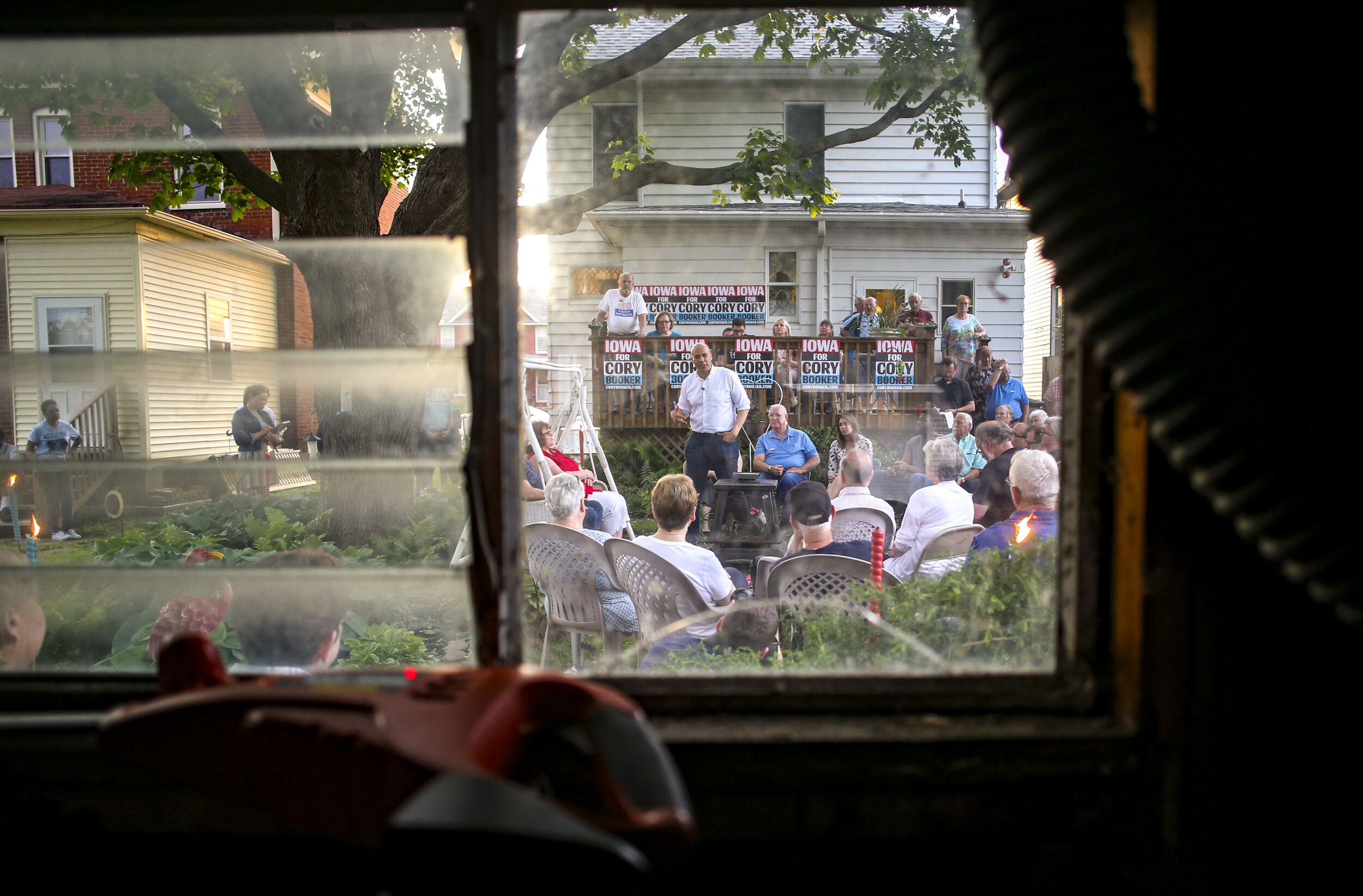  Seen from a detached garage, presidential hopeful Cory Booker speaks to gathered democrats at a backyard party in Muscatine, Iowa, Saturday.  