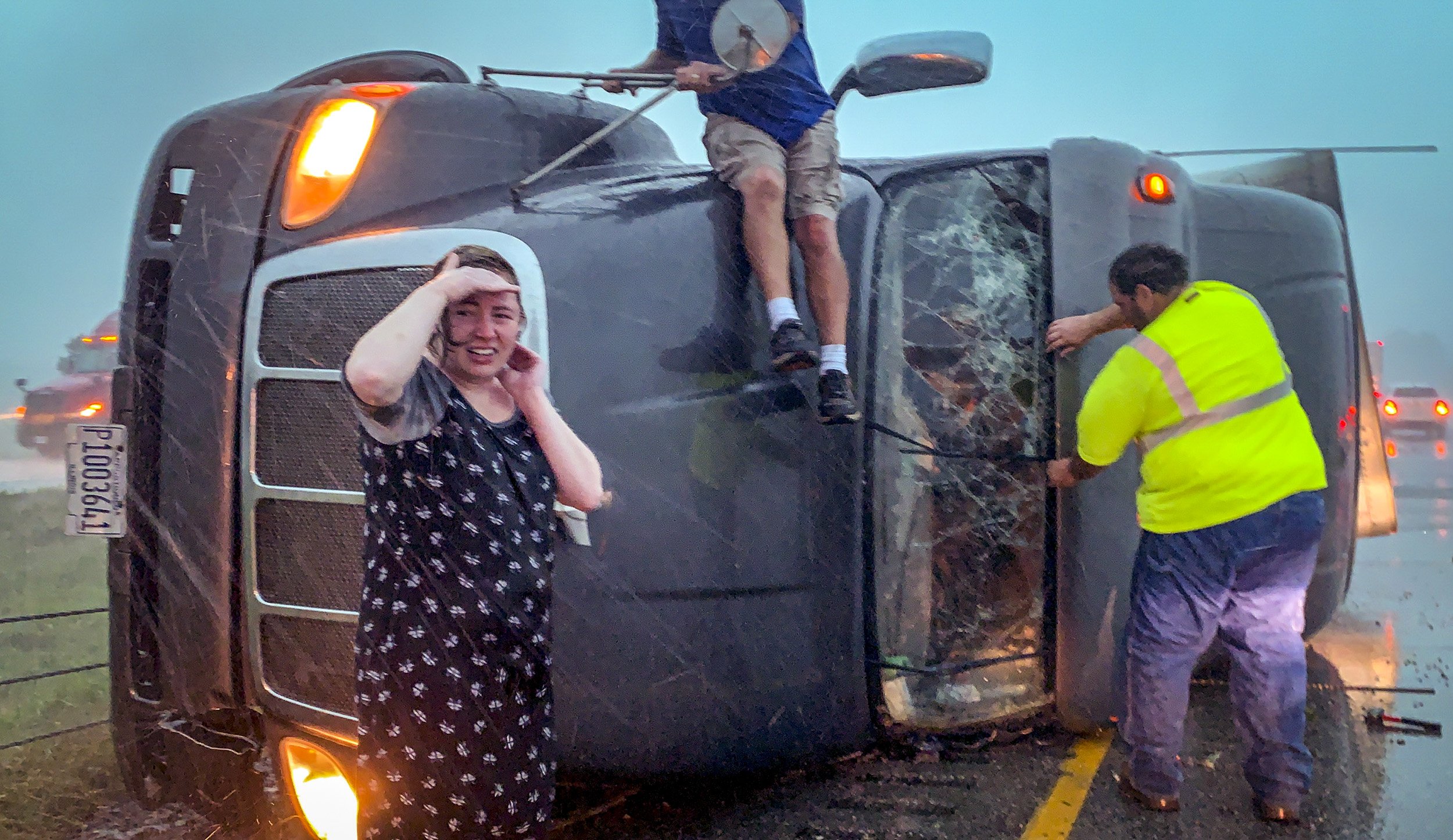  Passing motorists stop to help the driver of a tractor trailer after it was overturned laying down on the side of Interstate 380 in Cedar Rapids on Monday. Two men worked to remove the windshield and the woman, a registered nurse, made her way into 