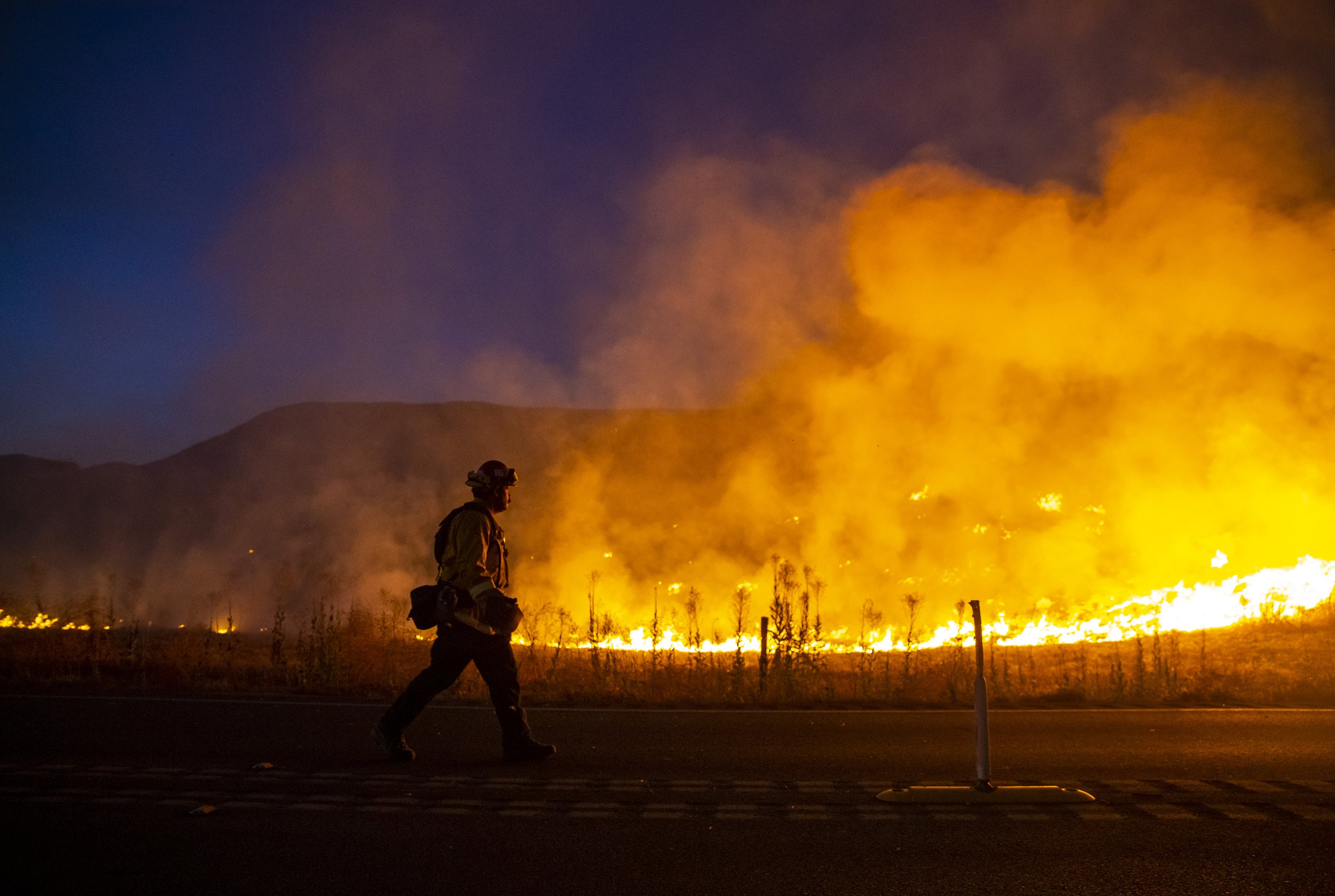  A firefighter walks down Gillman Springs Road while working to contain the Rabbit Fire in Moreno Valley, Calif., Friday.  