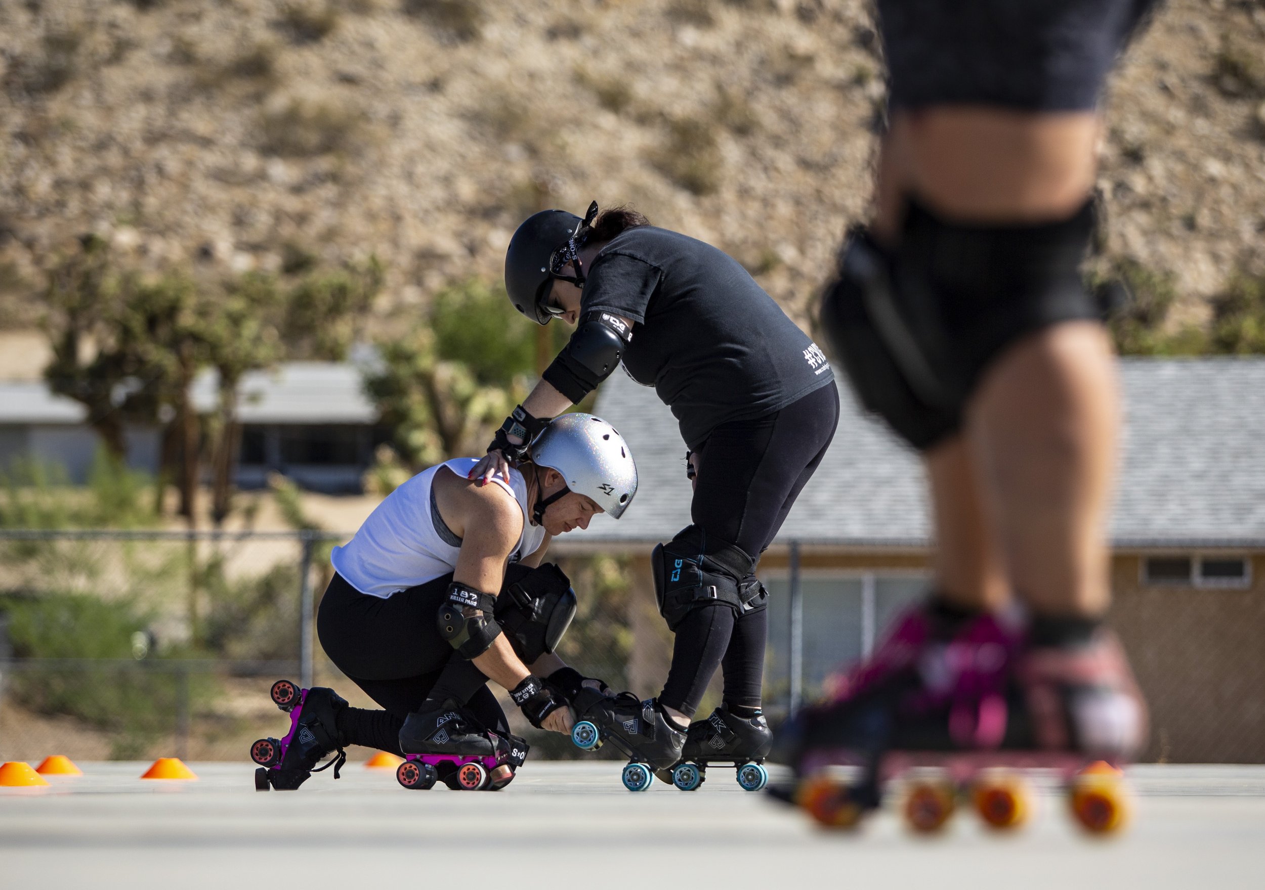  Ginny Broderick kneels down to help re-lace teammate Amanda Dela Rosa’s skates during practice at Brehm Park Family Recreation Center in Yucca Valley, Calif., Saturday.  