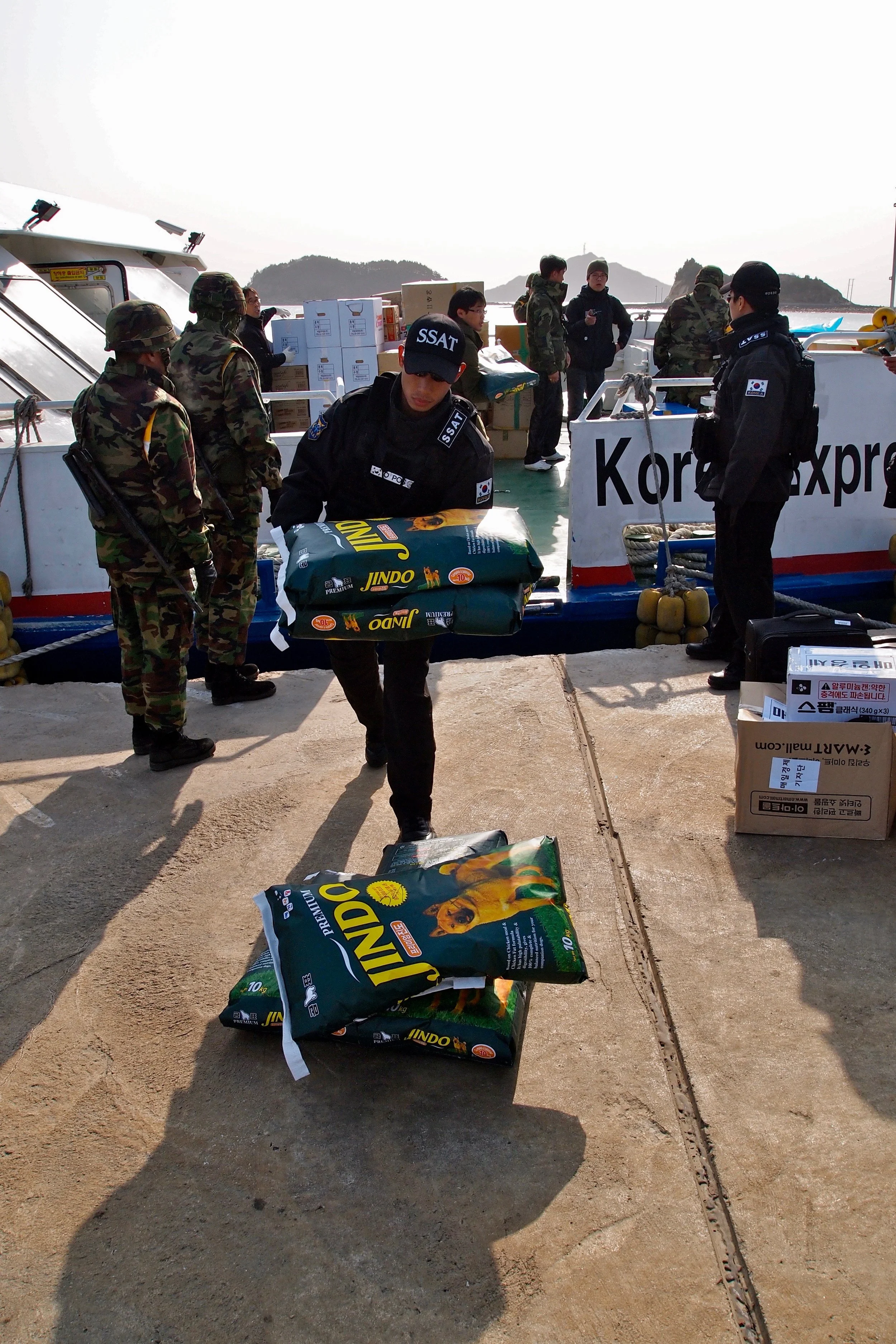 South Korean military personnel off loading dog food from a ferry at Yeonpyeong Island, which was evacuated after being hit by shelling from North Korea. (C) Remko Tanis