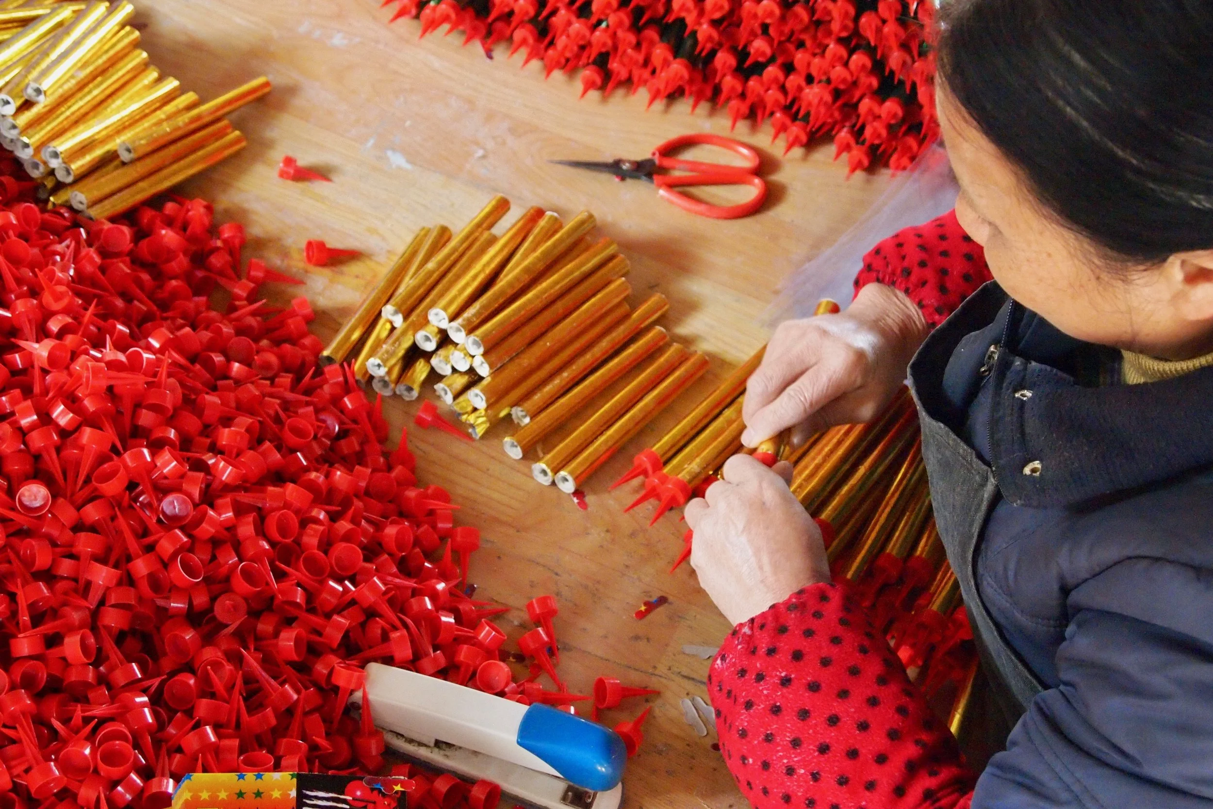 An employee putting caps on fireworks tubes at Dream Fireworks factory in Liuyang, China. Photo: (C) Remko Tanis