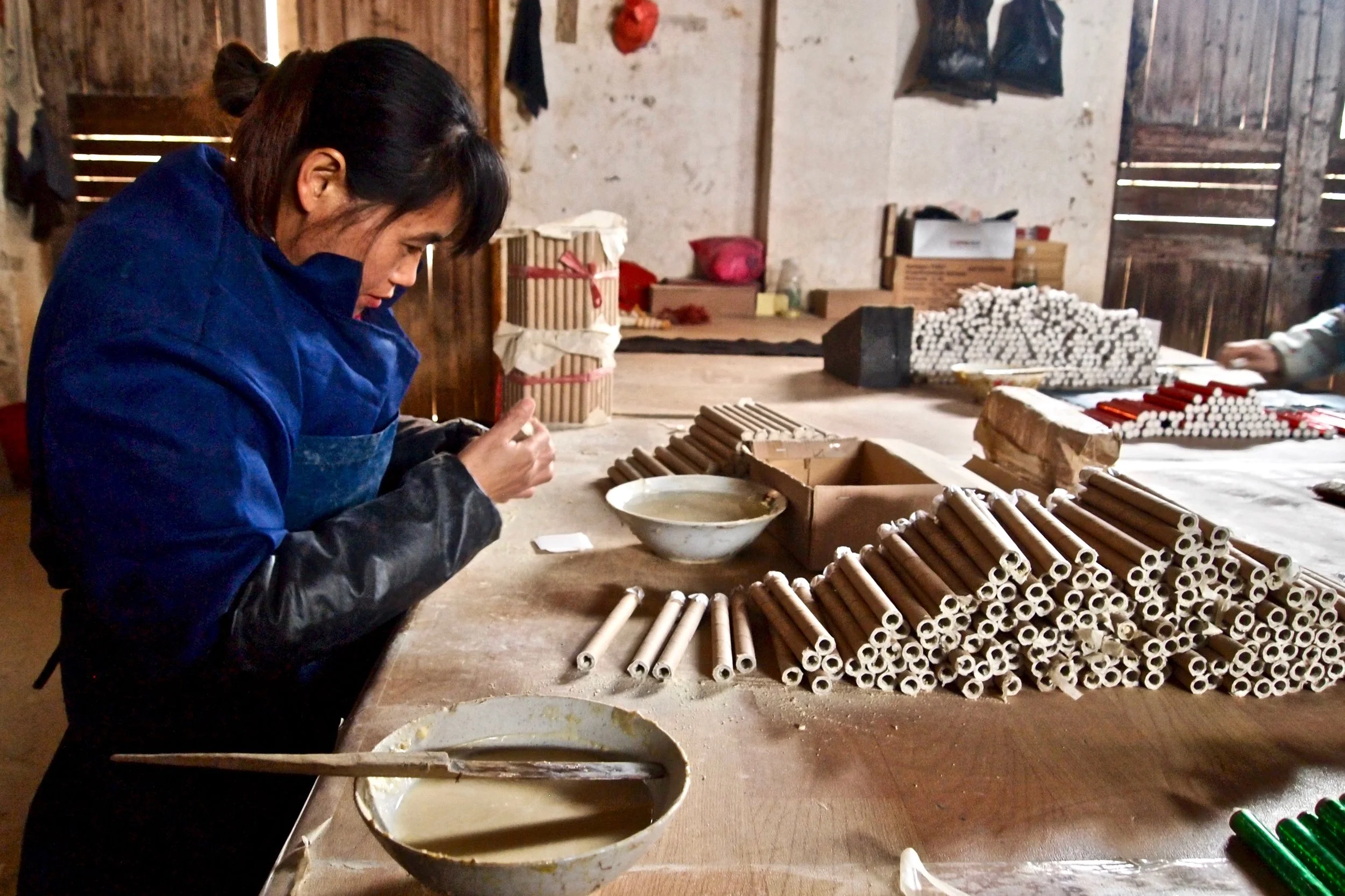 An employee of Dream Fireworks in Liuyang, China, glueing tubes together. Photo: (C) Remko Tanis