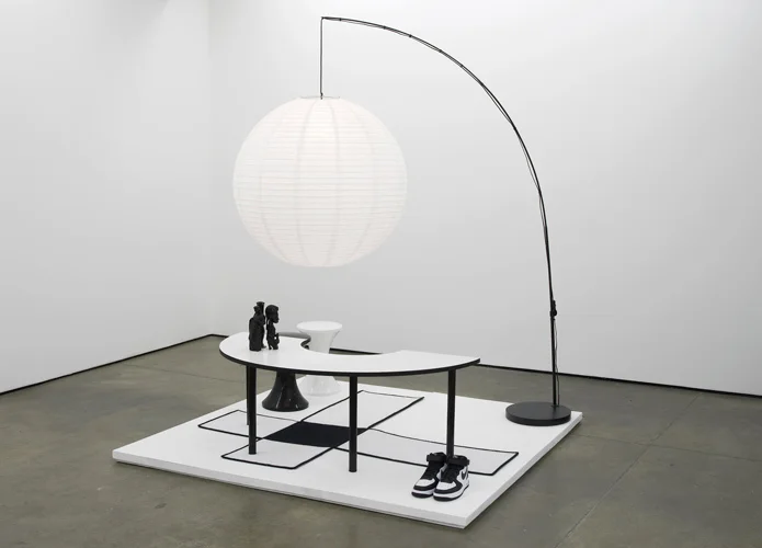 Untitled: Furniture Island No. 8 2012 Eliterank carpet, oversize Chinese Globe paper lantern, Branex Tam Tam stools, Costcutter Arc classroom table, Jesus figurine, vintage African carving, acrylic bong, Nike Air Force 1’s 200 x 200 x 200 cm