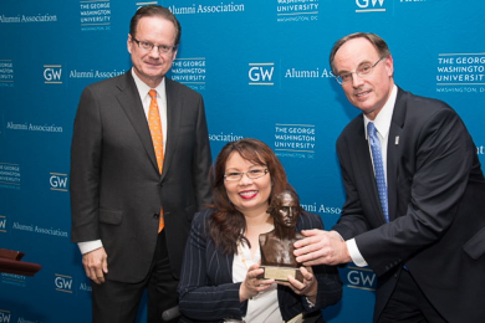 GW Alumni Association President Steve Frenkil, right, and Elliott School of International Affairs Dean Michael Brown present the Distinguished Alumni Achievement Award to Rep. Tammy Duckworth.