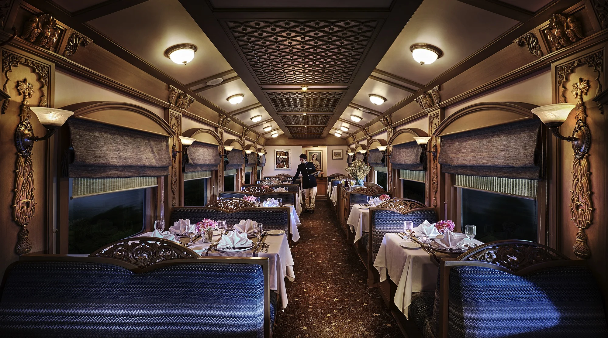 Deccan Odyssey luxury dining carriage with ornate woodwork, blue seating and formally set tables