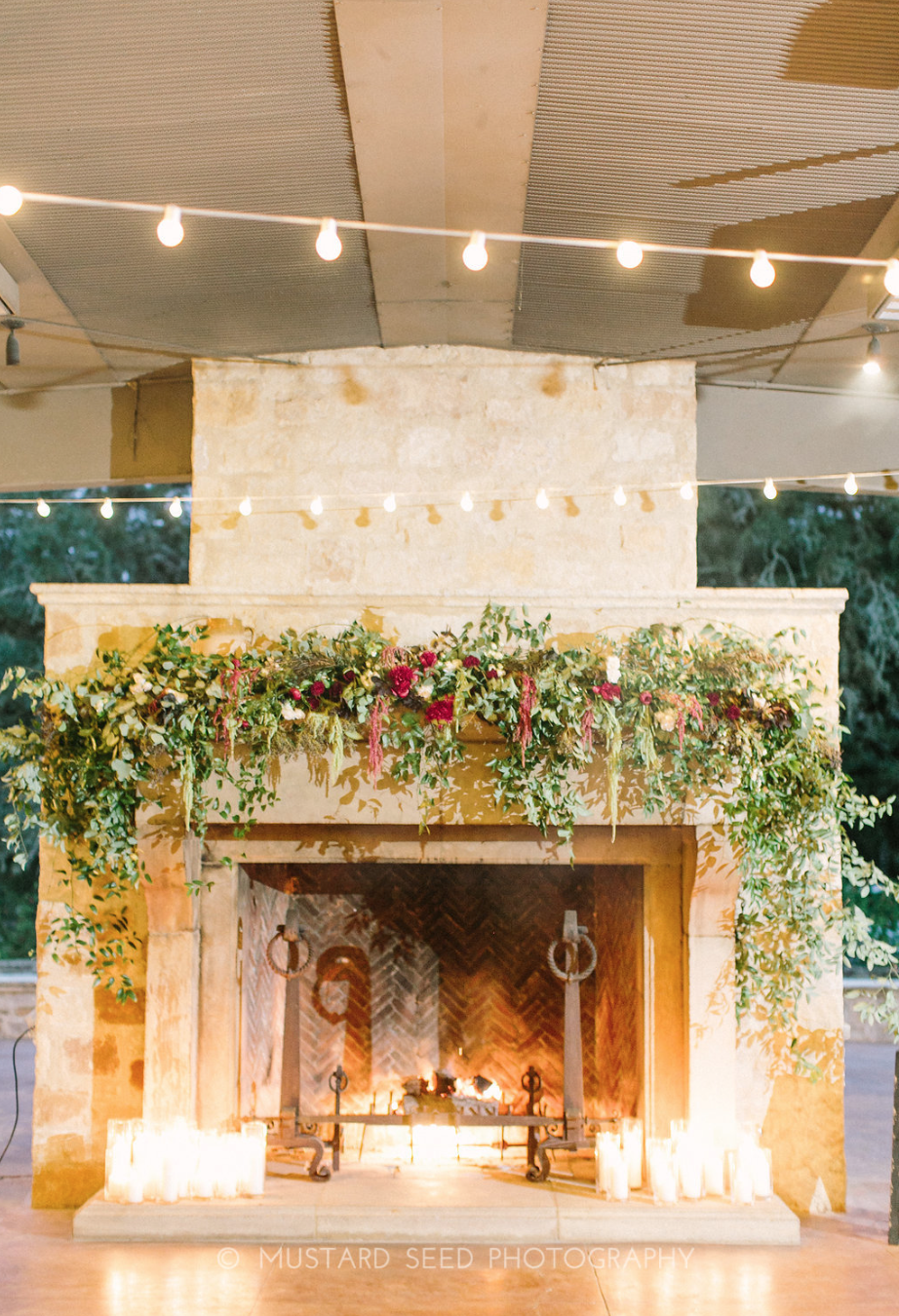 Fireplace with hanging greenery and candles by Maxit Flower Design in Houston, TX.